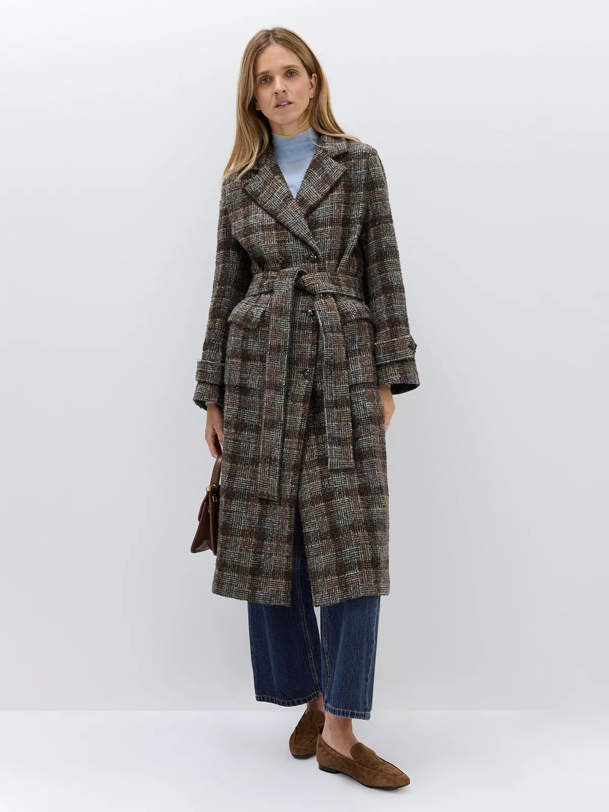 Front view of model in Dark Brown wool alpaca tweed check coat with belt tied, hands in pockets, over a light top and wide-leg jeans.