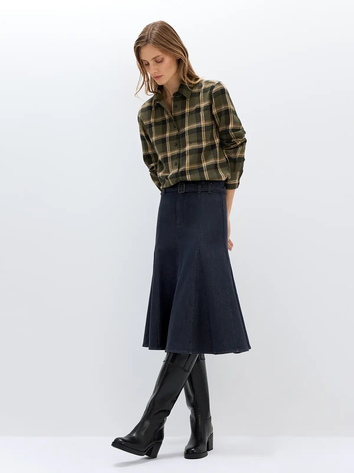 Side view of a model wearing a Dark Blue fishtail denim skirt with belt, plaid shirt, and boots.