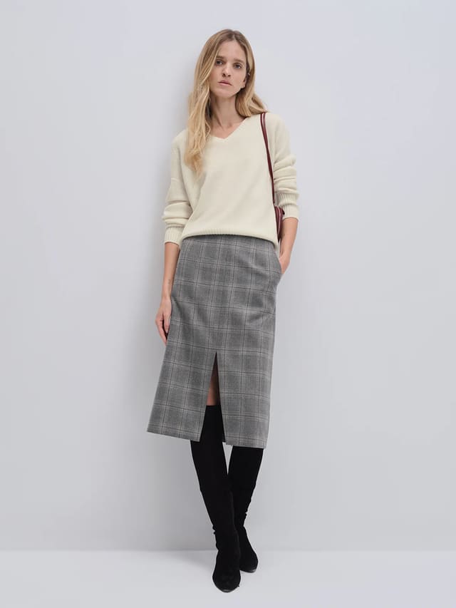 Model wearing andreatang pure wool blue-grey check midi skirt with front vent, styled with ivory knit and black boots
