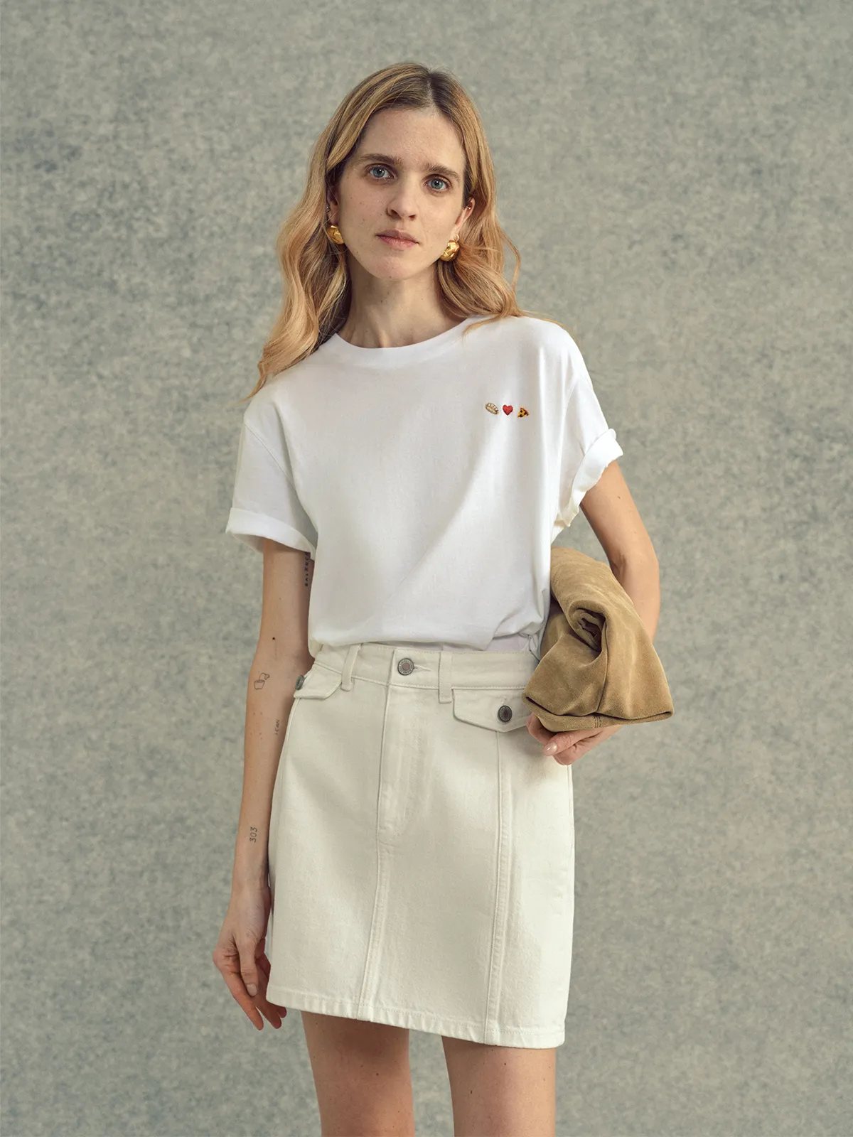 Woman in white embroidered Lover's T-Shirt paired with mini denim skirt and suede jacket