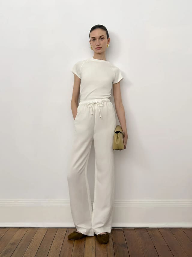 andreatang LUCA white fitted t-shirt with white wide-leg trousers and olive loafers, full-body side pose