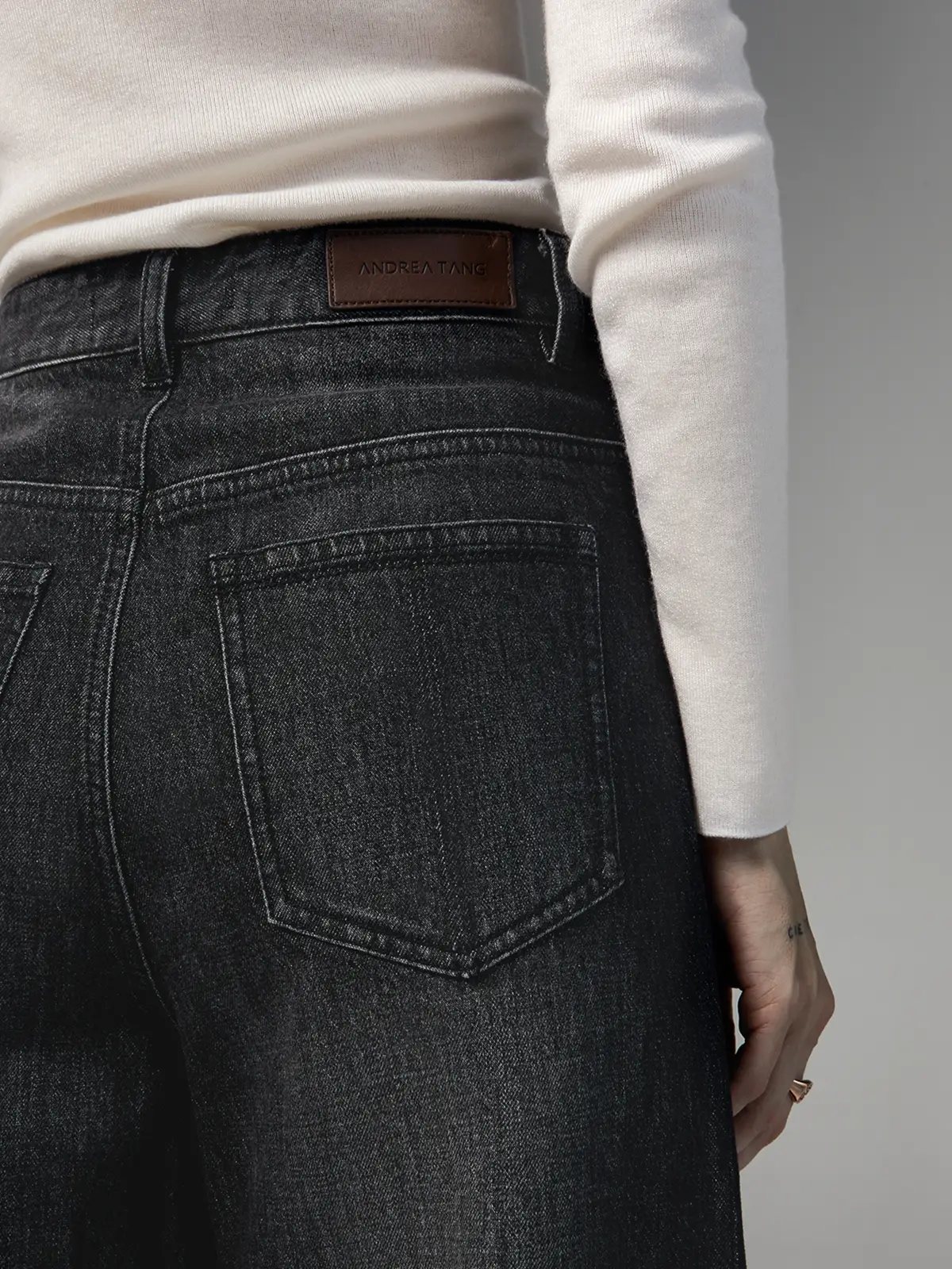 Back view close-up of Dark Grey wide-leg jeans showing the waistband with a leather brand patch.