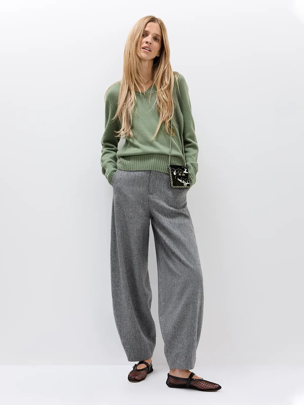 Front view of a model in a Merino Wool V-Neck Jumper with light-colored pants and a shoulder bag.