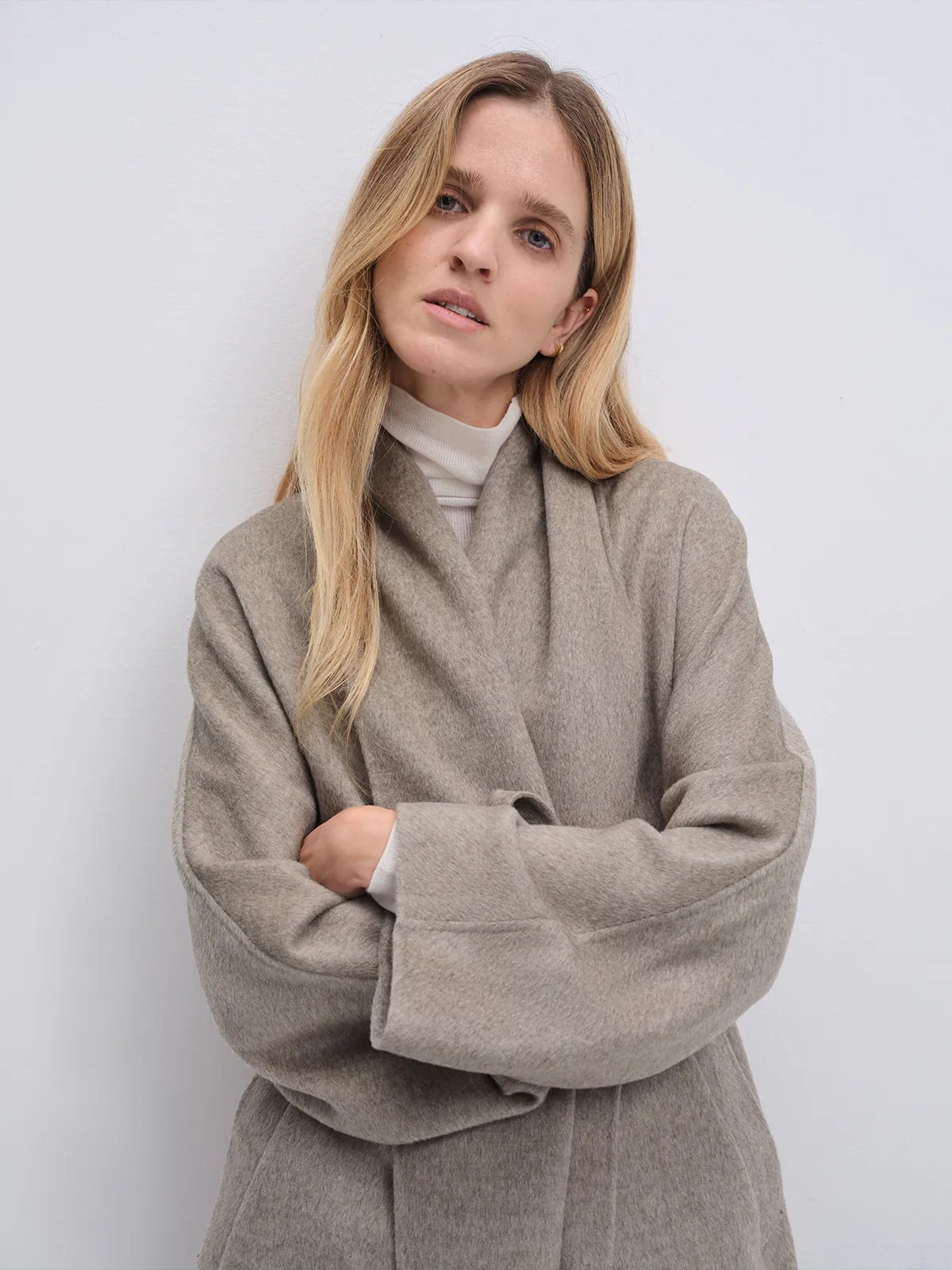 Model in a Taupe yak wool robe coat with arms crossed, showing the draped collar and relaxed fit.