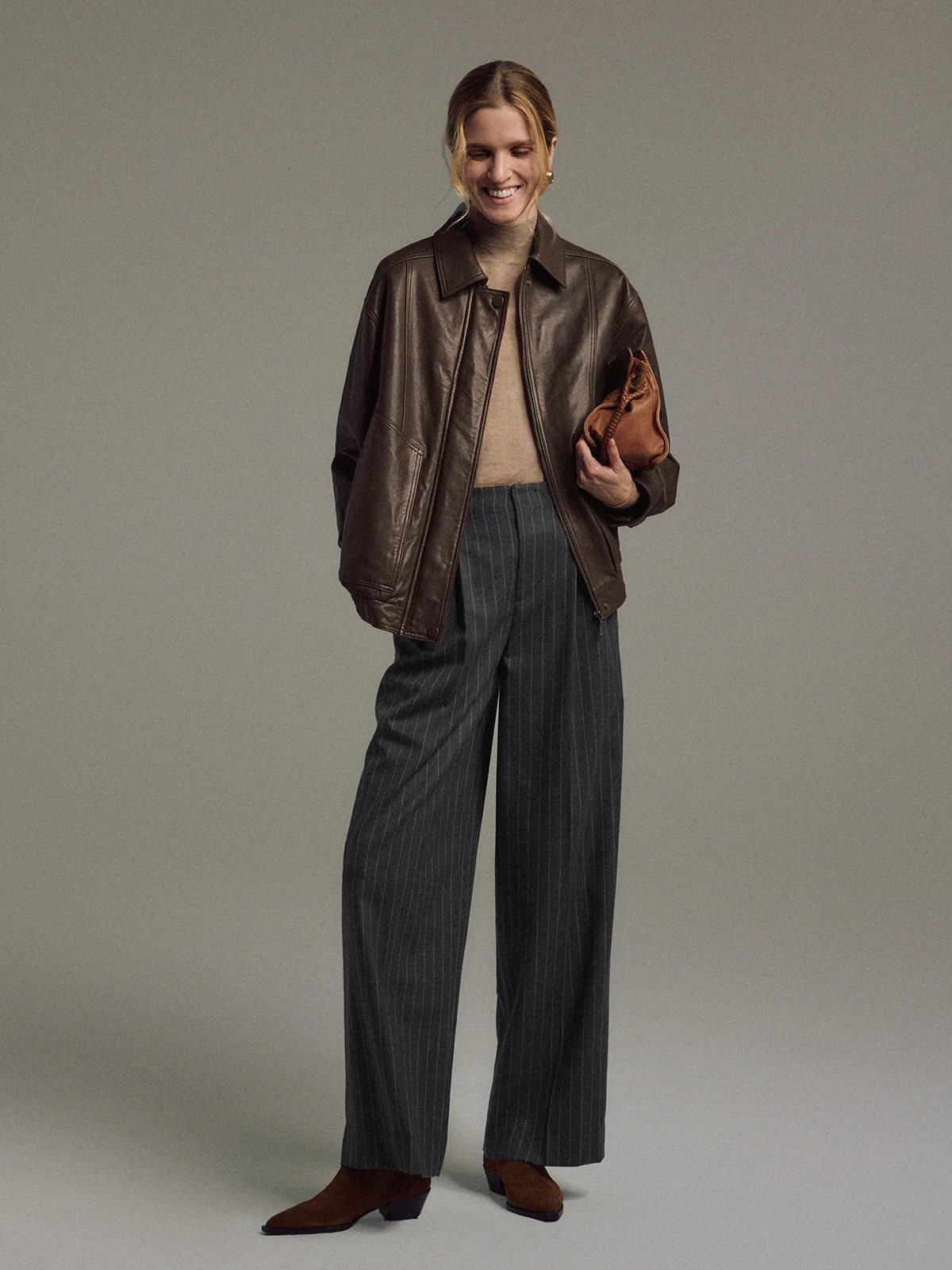 Model wearing Dark Gray wool striped wide-leg trousers with cable-knit sweater and clutch.