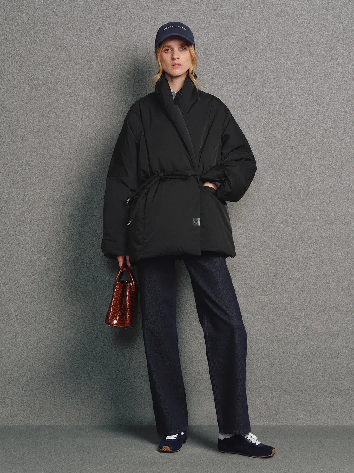 Front view of the Black OPHELIA relaxed wrap-style down coat worn open over a turtleneck, hands in pockets.