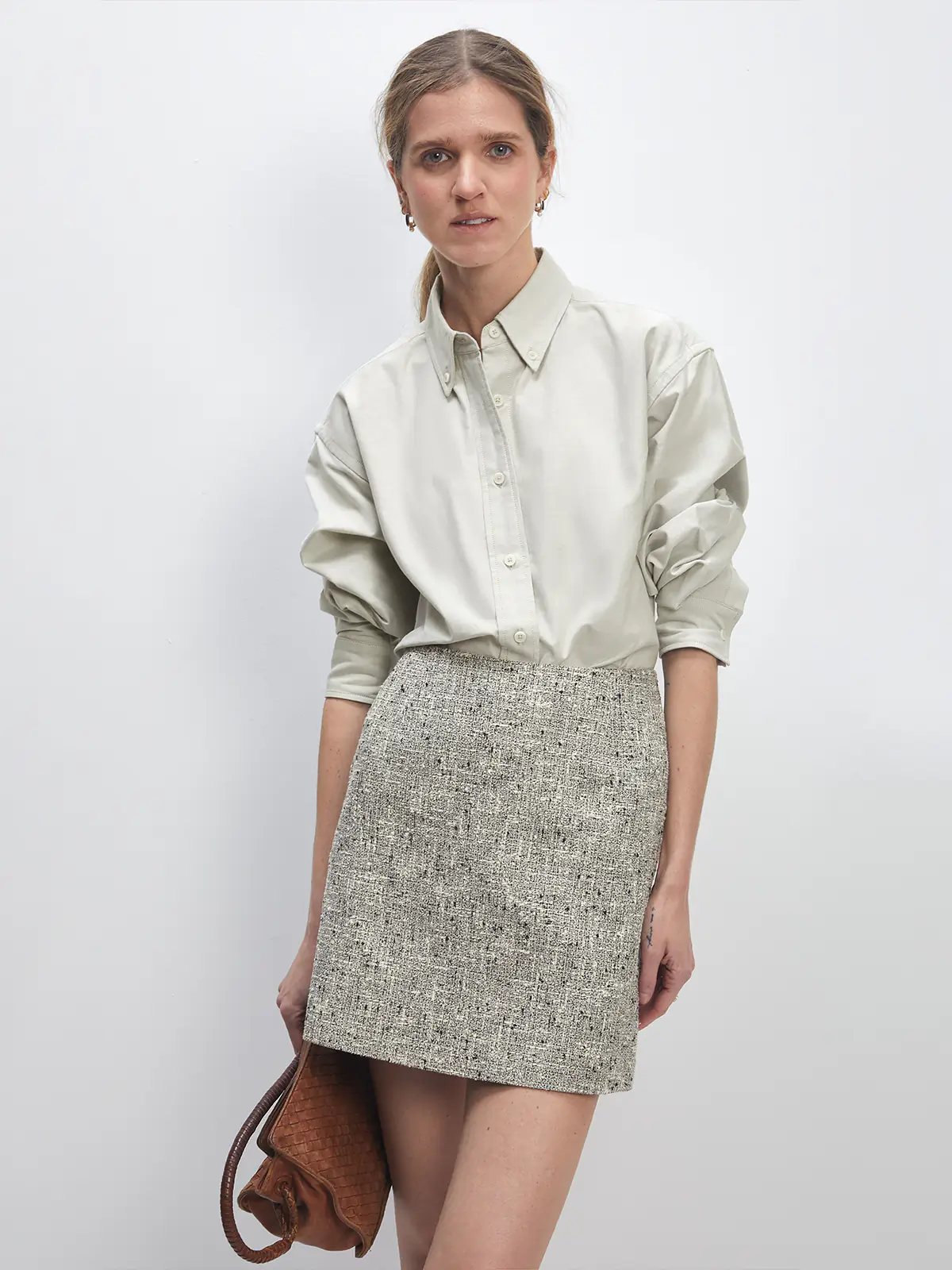 Front view of the loose Oxford shirt in Slate Gray worn with wide-leg denim and slip-on shoes, hand in pocket.