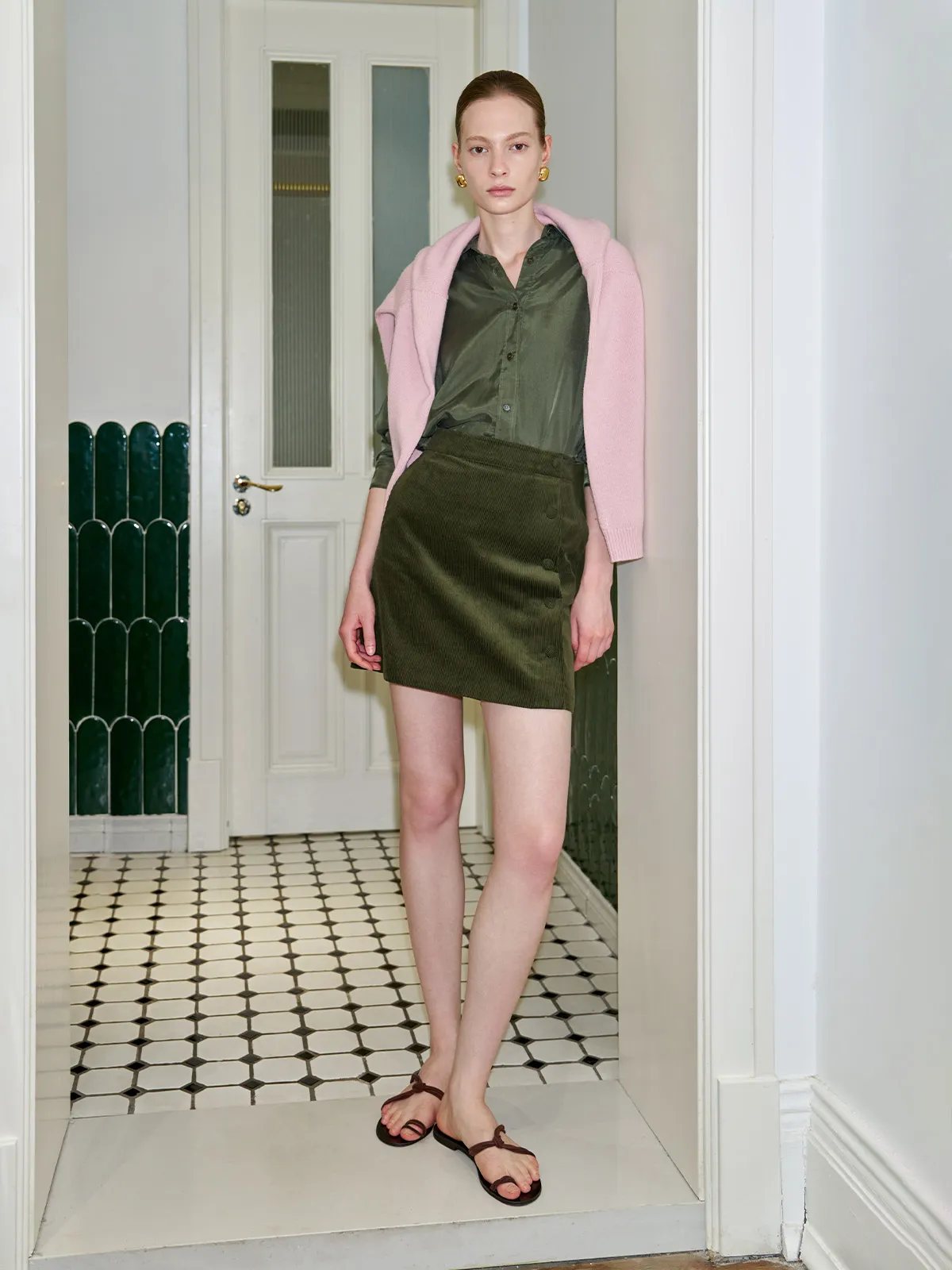 Andreatang GREER olive cupro relaxed shirt styled with pink knit cardigan and corduroy mini skirt in vintage hallway
