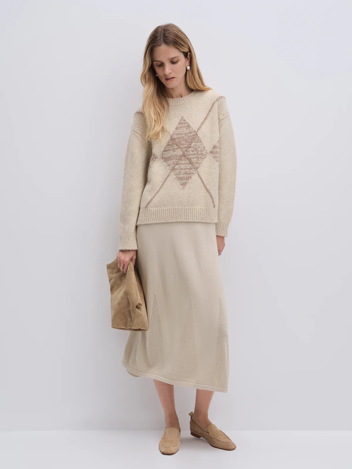 Model wearing the Oatmeal PHOEBE alpaca cotton jacquard jumper with diamond pattern, paired with trousers and holding a clutch.