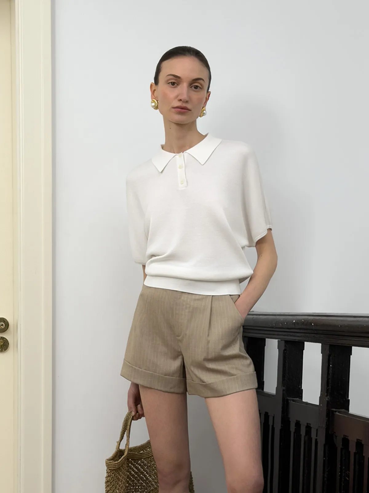 NADINE white knit polo with beige pleated shorts and raffia tote, minimalist summer styling