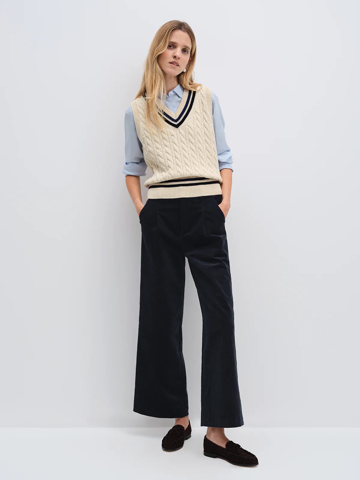 andreatang cable-knit cricket vest layered over light blue shirt with wide-leg navy trousers