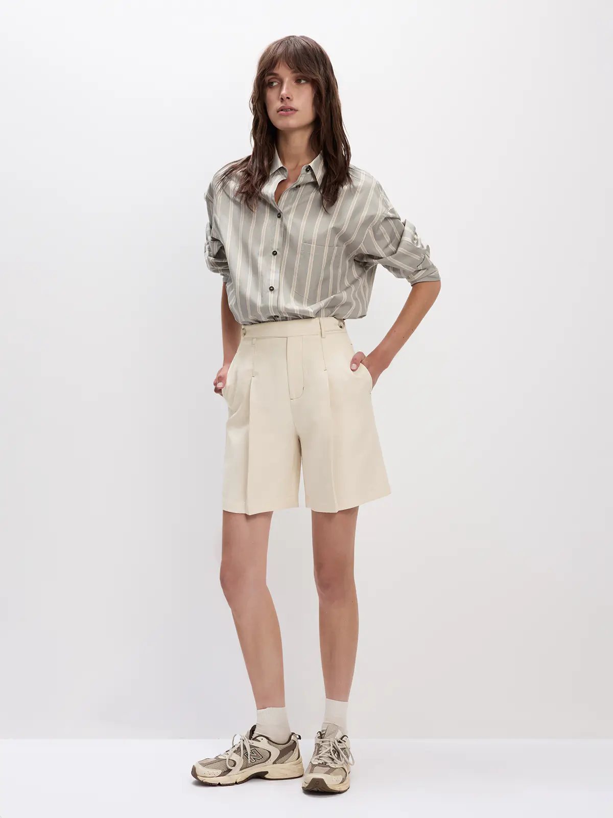 Model in a Grey striped oversized cotton shirt with rolled sleeves and chest pocket, hands in pockets.