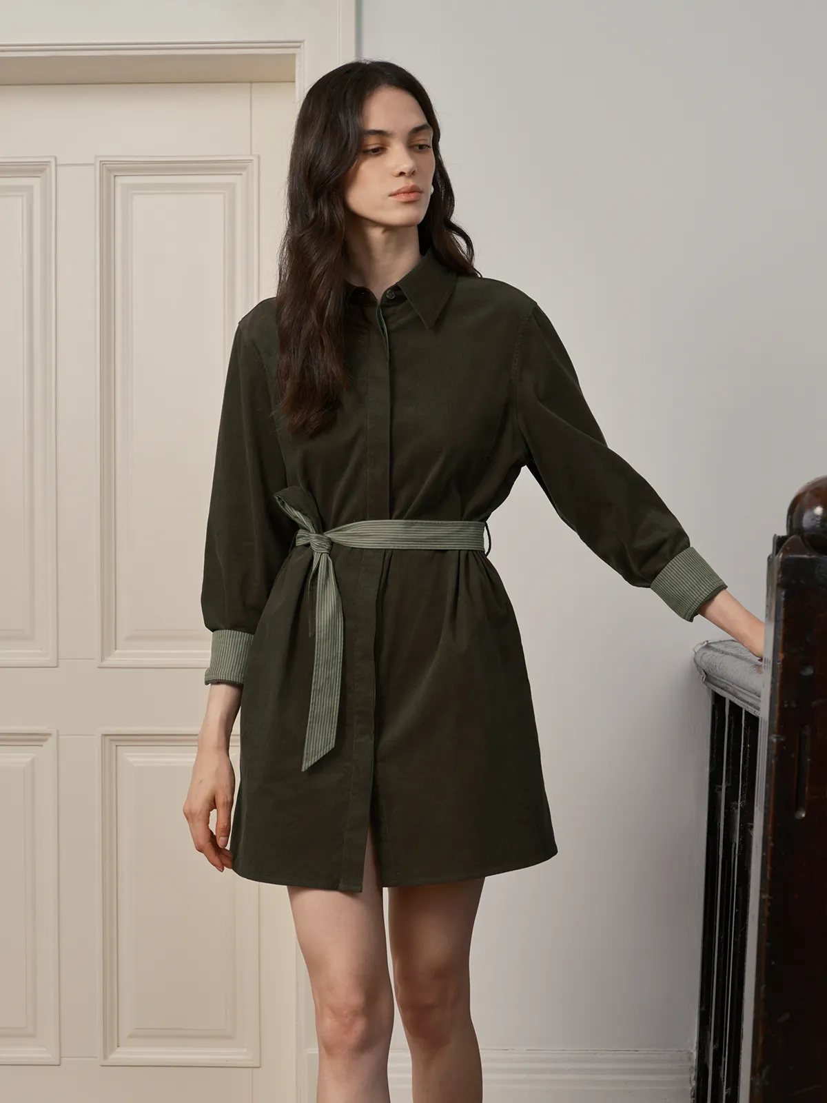 JILLIAN dress side profile with model leaning on banister, showcasing drape and fit