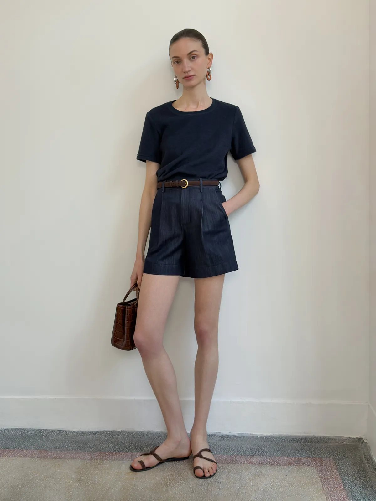 Model wearing RANGER suede leather belt with navy cotton tee and high-waisted denim shorts, minimalist styling against white wall