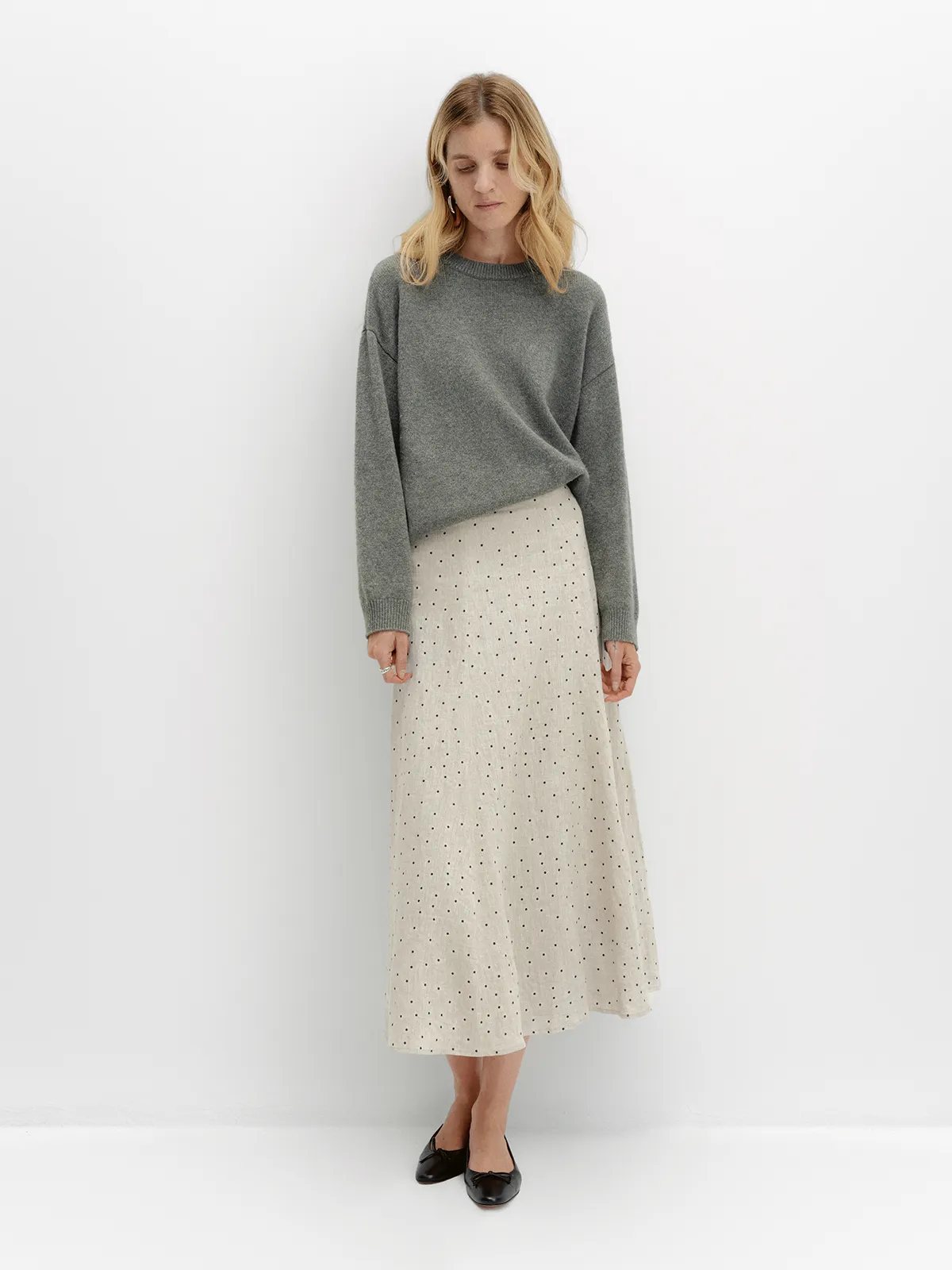 DOTTIE skirt with grey oversized sweater, black ballet flats, model looking down