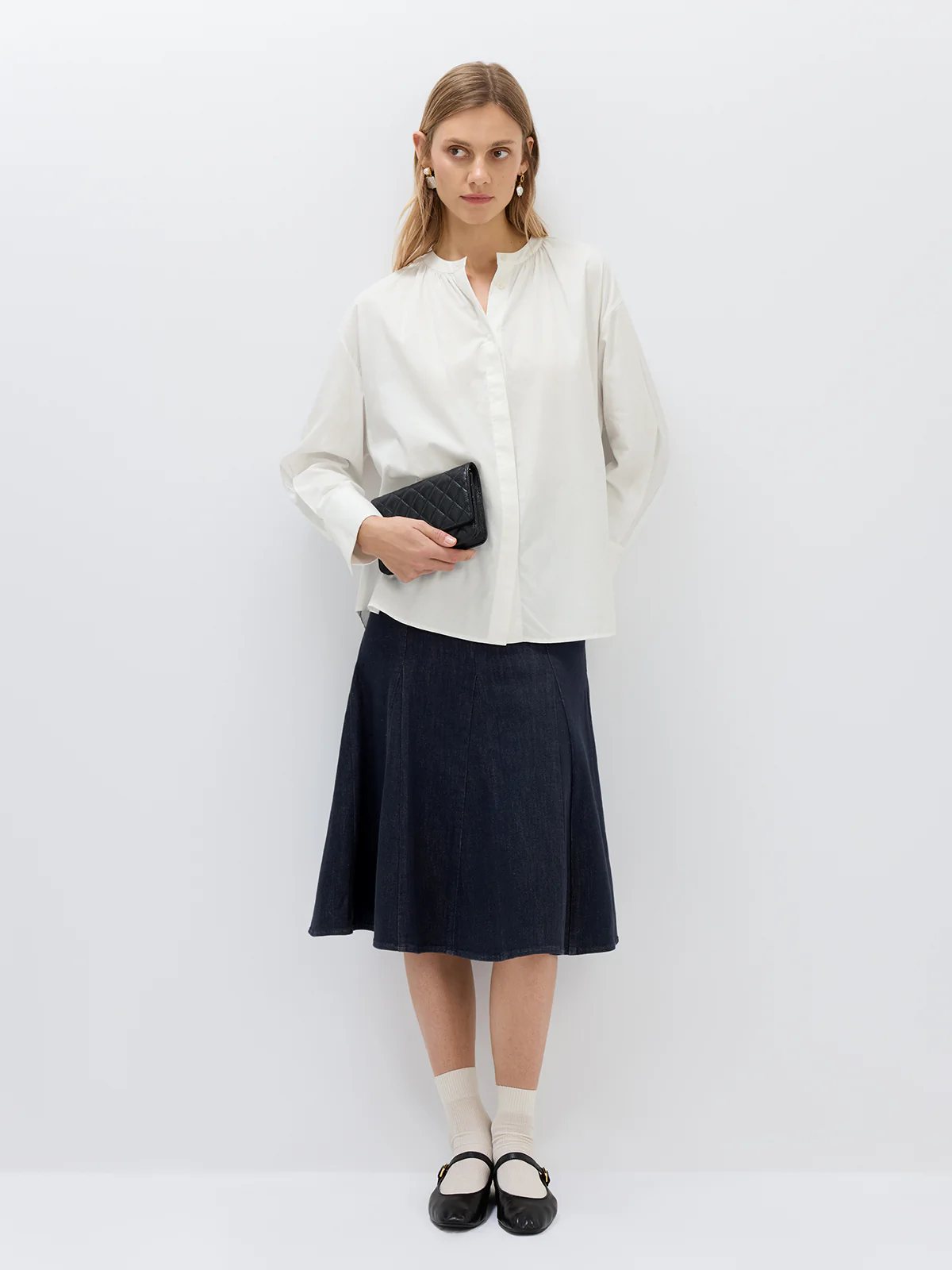 White textured blouse with open front and draped sleeves, worn over a dark skirt in a front-facing pose.