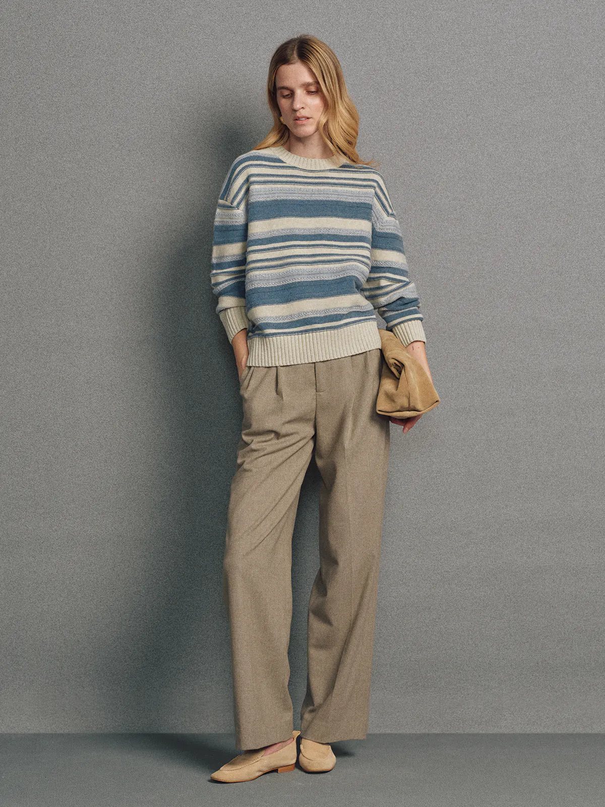 Side view of model in a brown irregular multicolour stripe wool cotton jumper with arms crossed.
