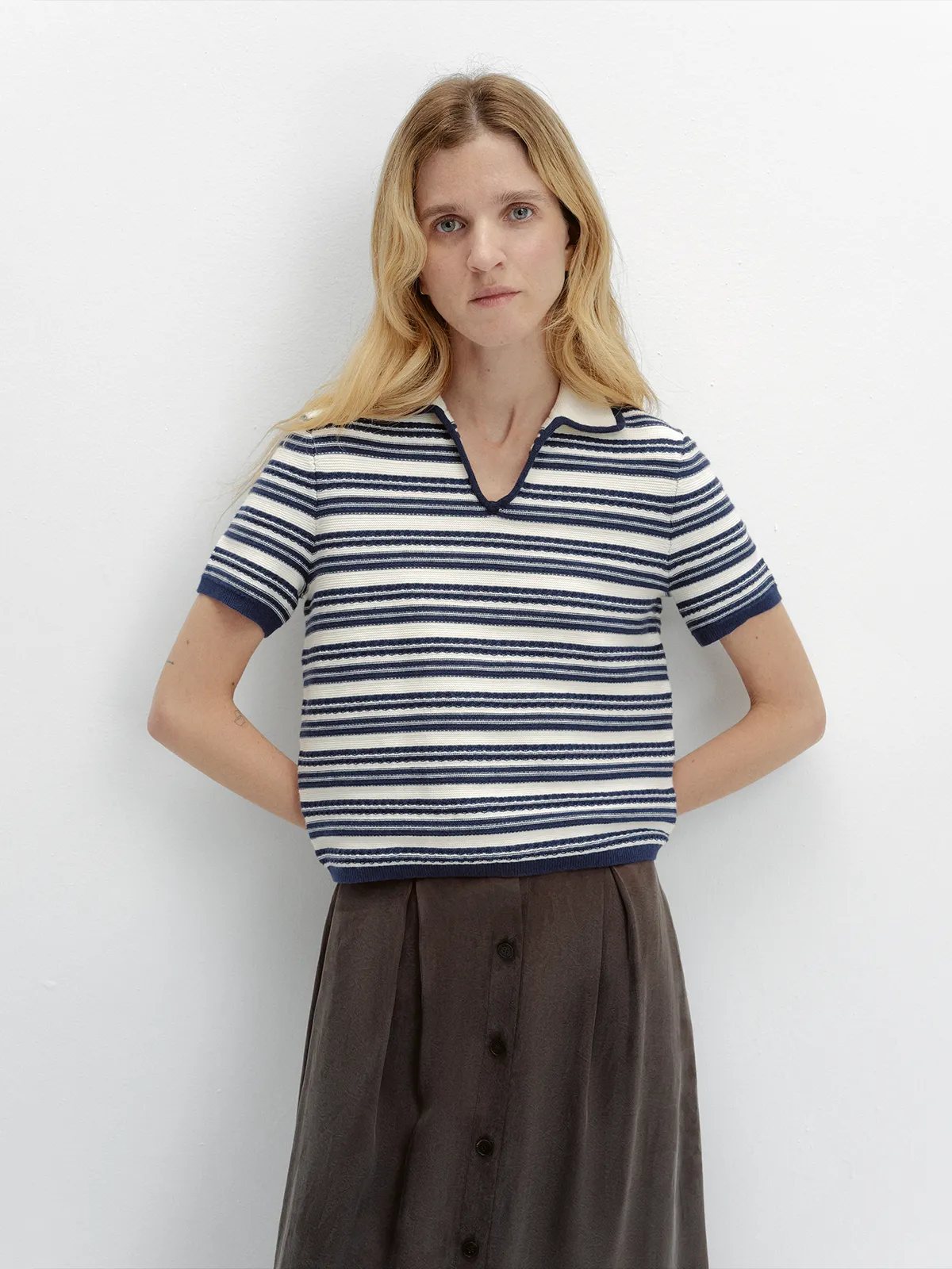 Front pose of model in ANGELINA striped polo with hands on hips, brown midi skirt