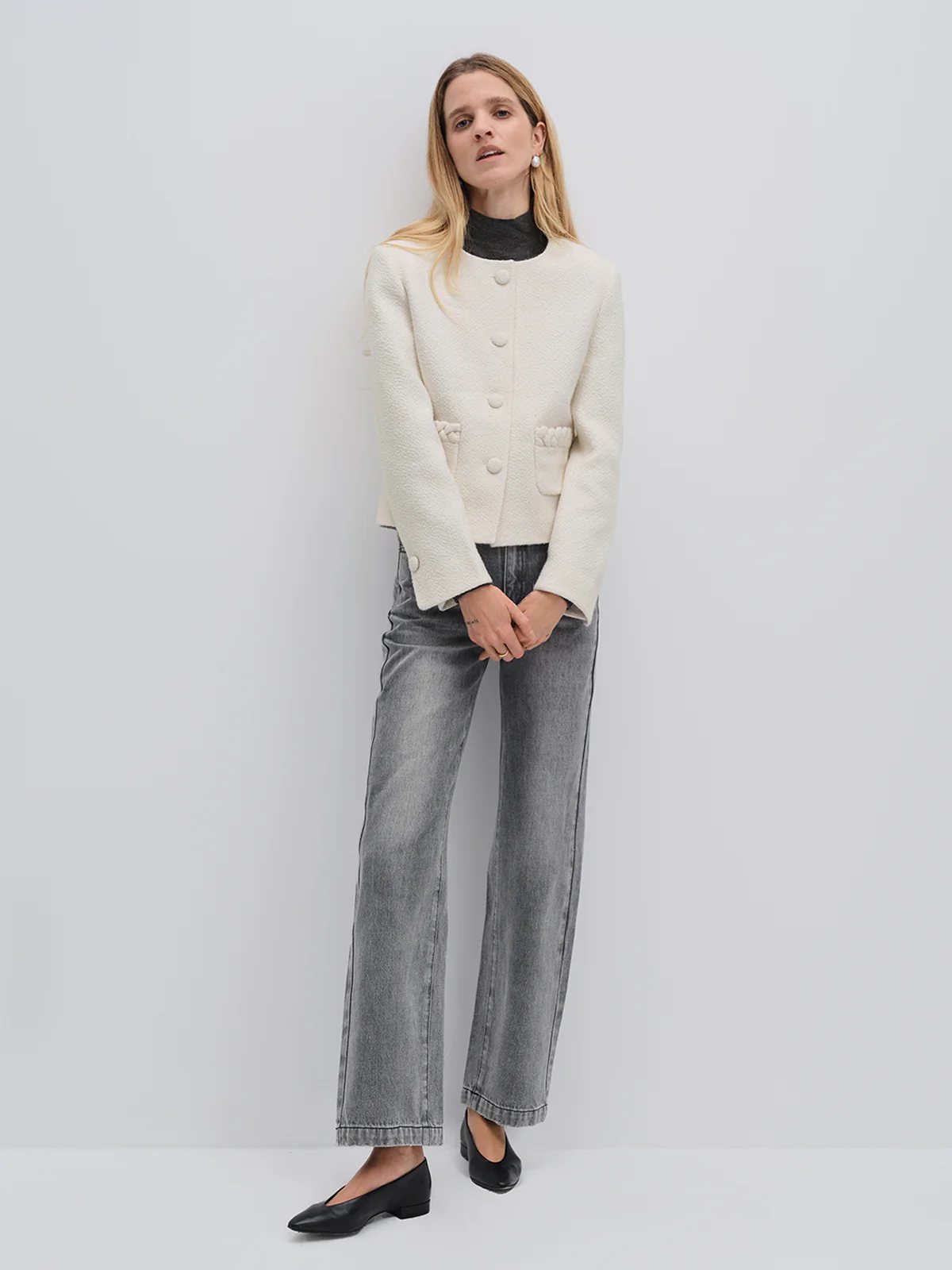 Front view of model in andreatang ivory tweed cropped jacket over charcoal turtleneck with grey denim