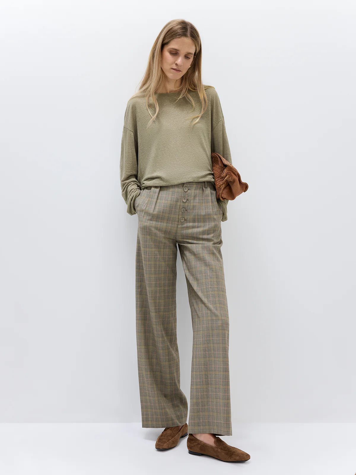 Model wearing wide-leg Prince of Wales check trousers with high waist and button closure, styled with vest and turtleneck.