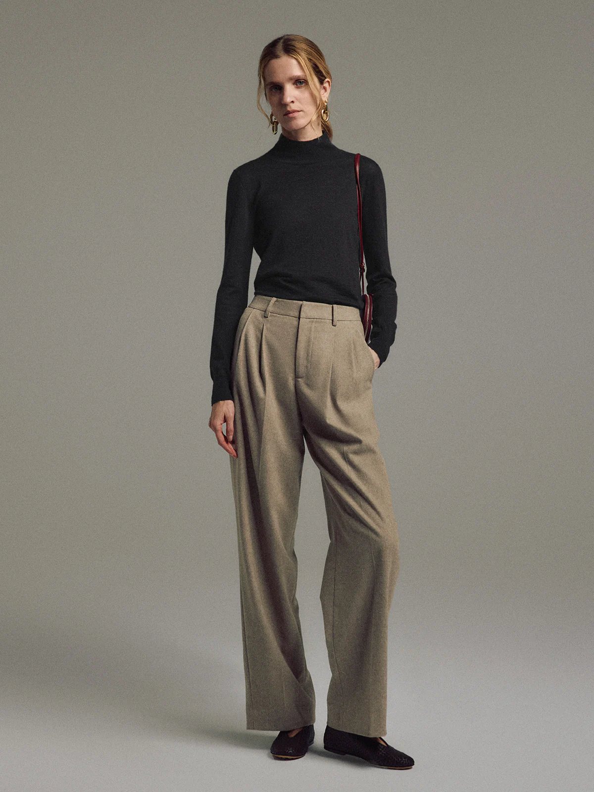 Model wearing Tan wool blend double-pleat straight-leg trousers with top and dark shoes, side view.
