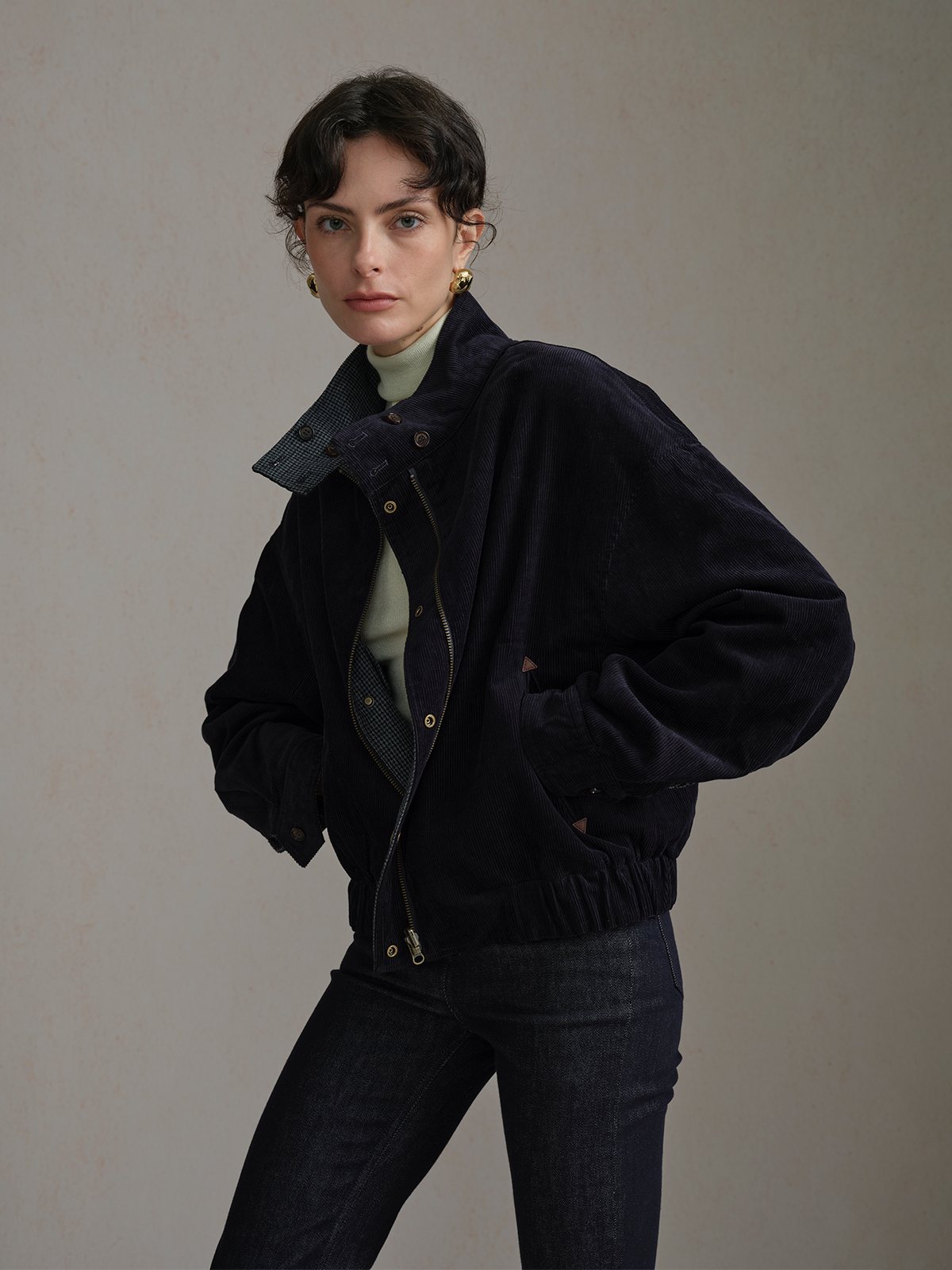 Front view of the Navy Andreatang CHARLIE corduroy side over a light high-neck top with dark jeans.