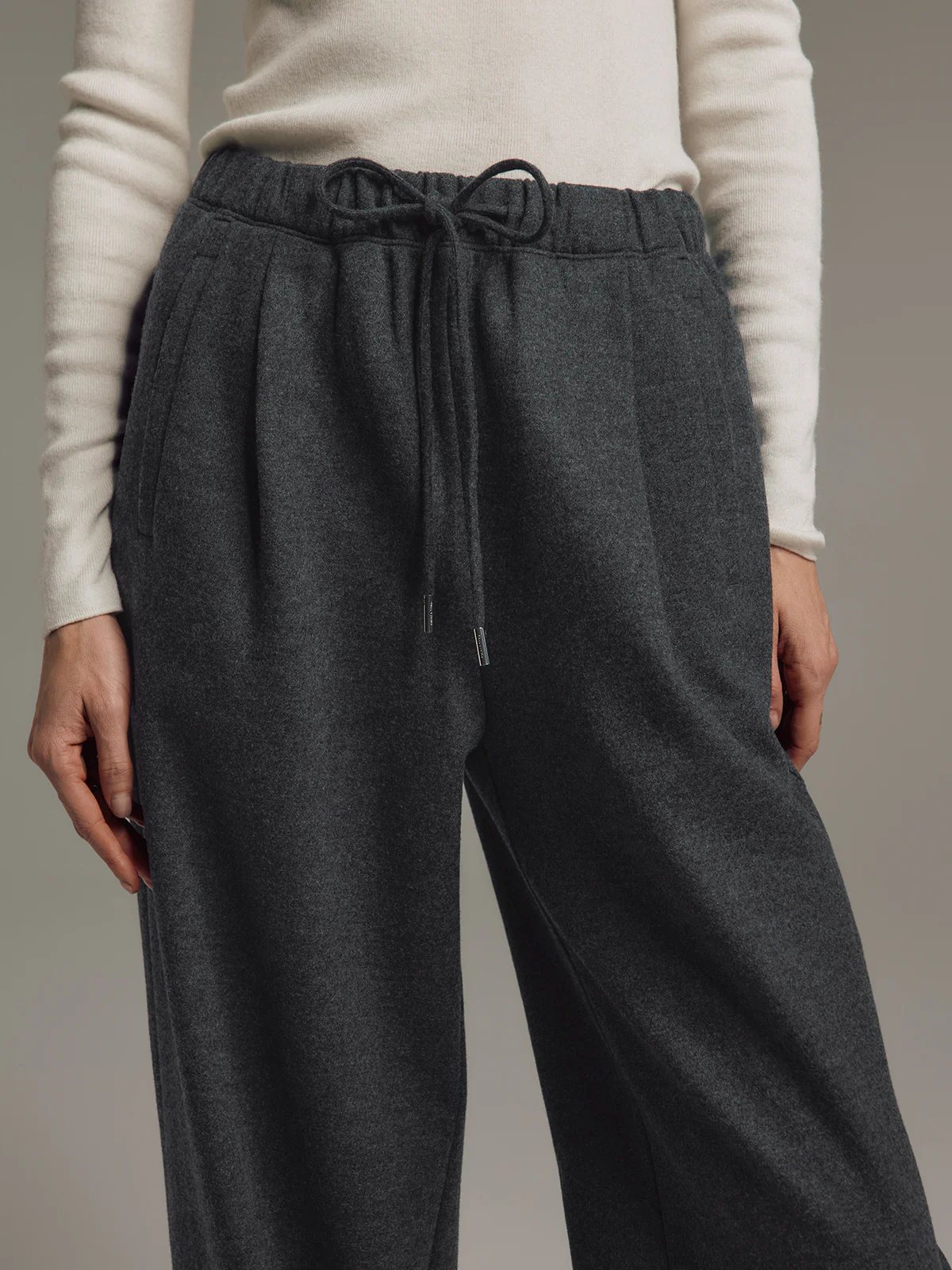 Side view of model in Dark Gray wool blend straight trousers with drawstring waist and relaxed fit.