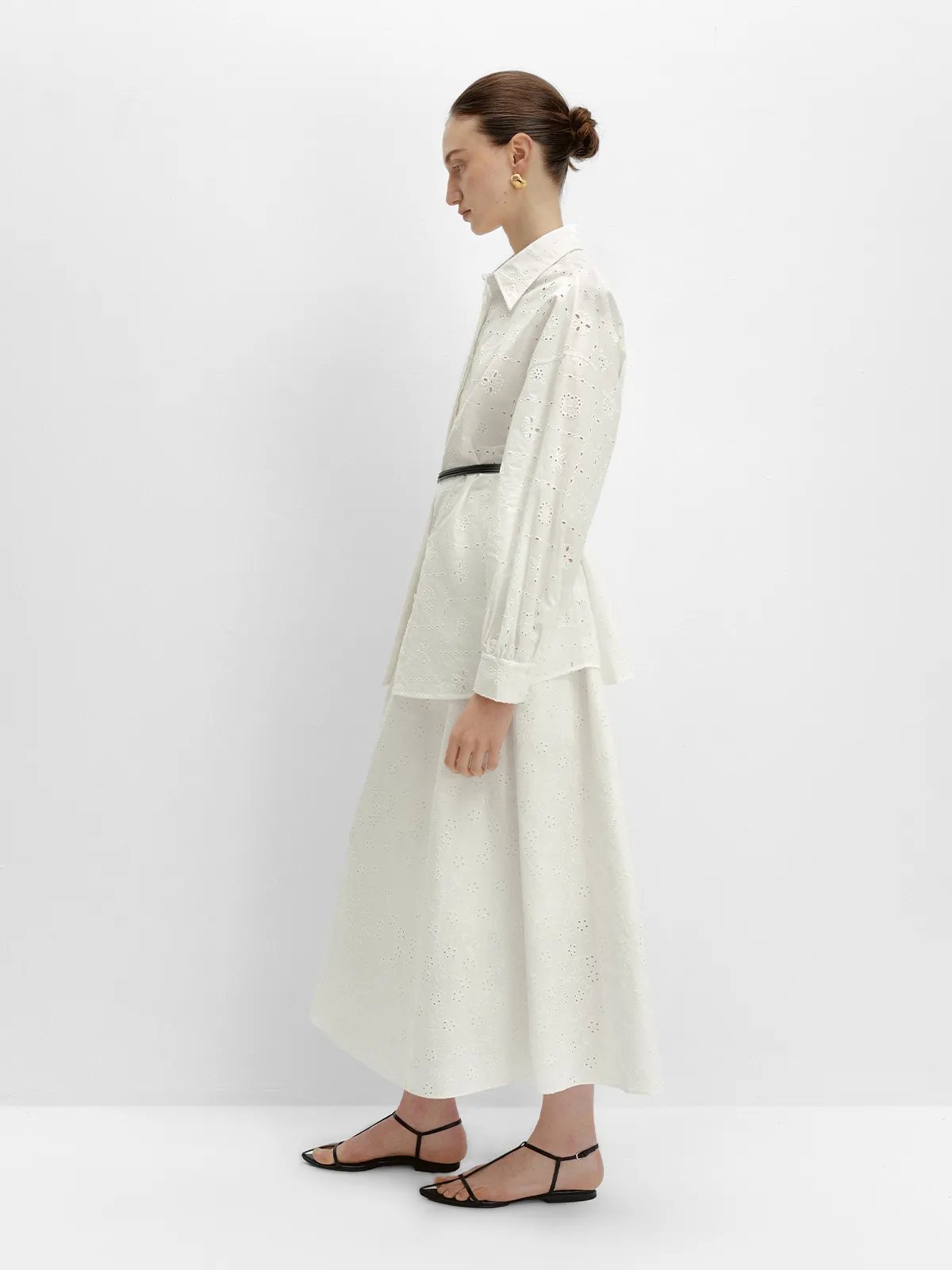 Side profile of MINA shirt belted with black waistband, paired with white midi skirt and strappy sandals