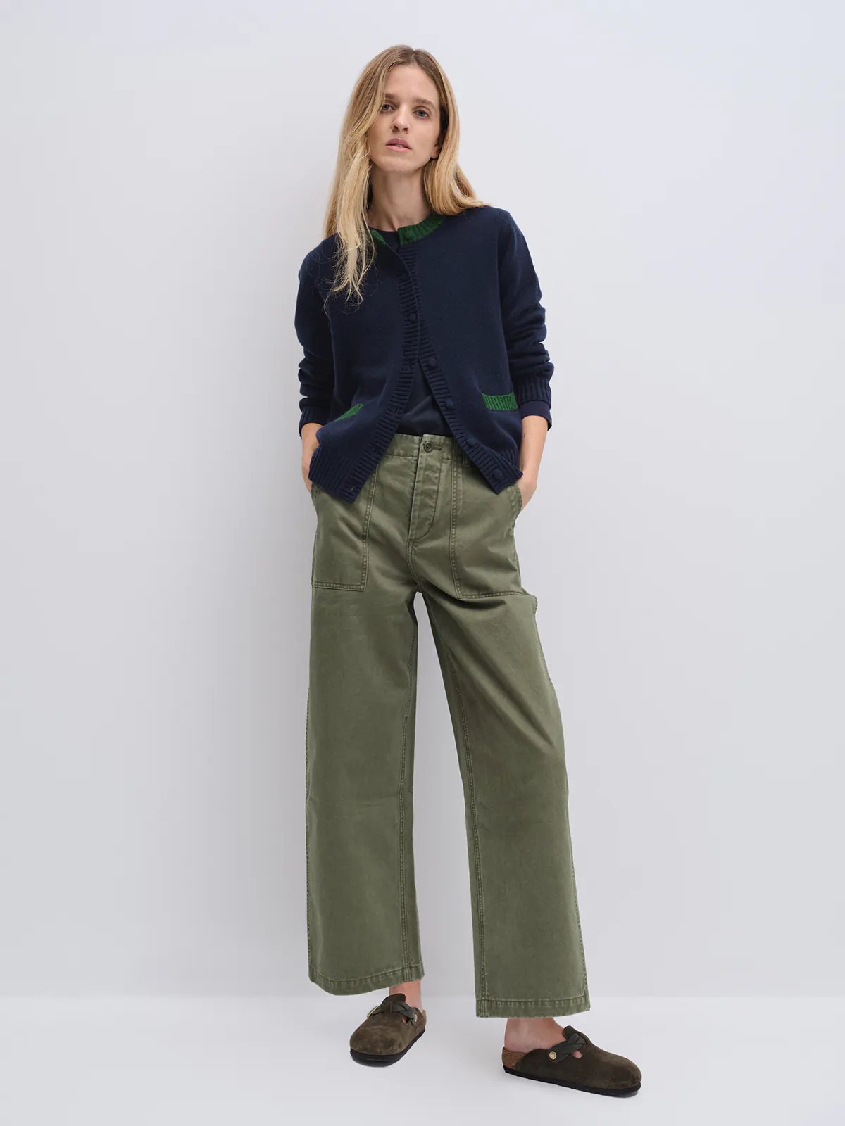 Model in olive green cotton utility trousers with wide legs, styled with a striped top and cap.