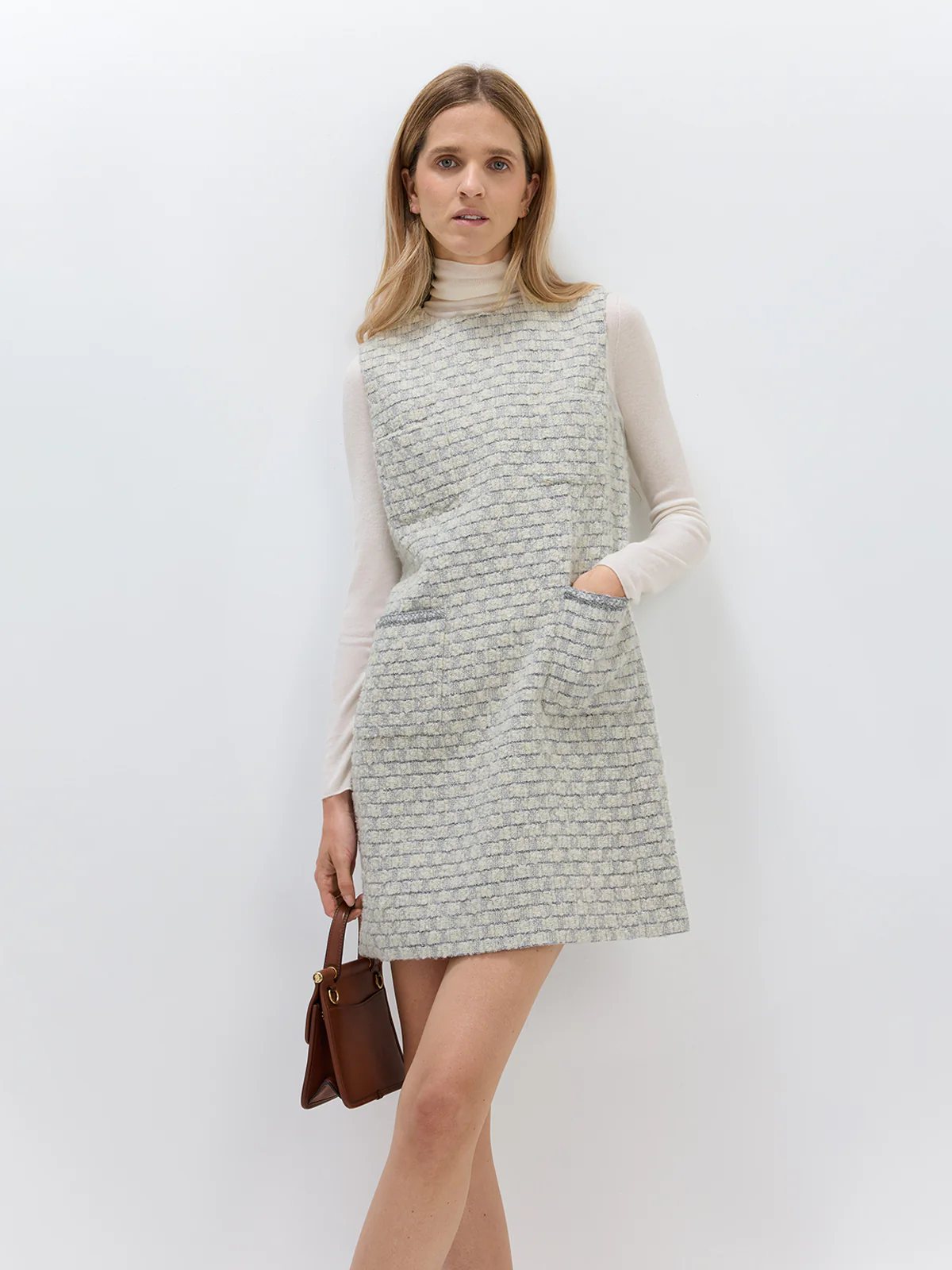 Front view of model in andreatang bouclé check sleeveless mini dress with ivory turtleneck and slingback heels
