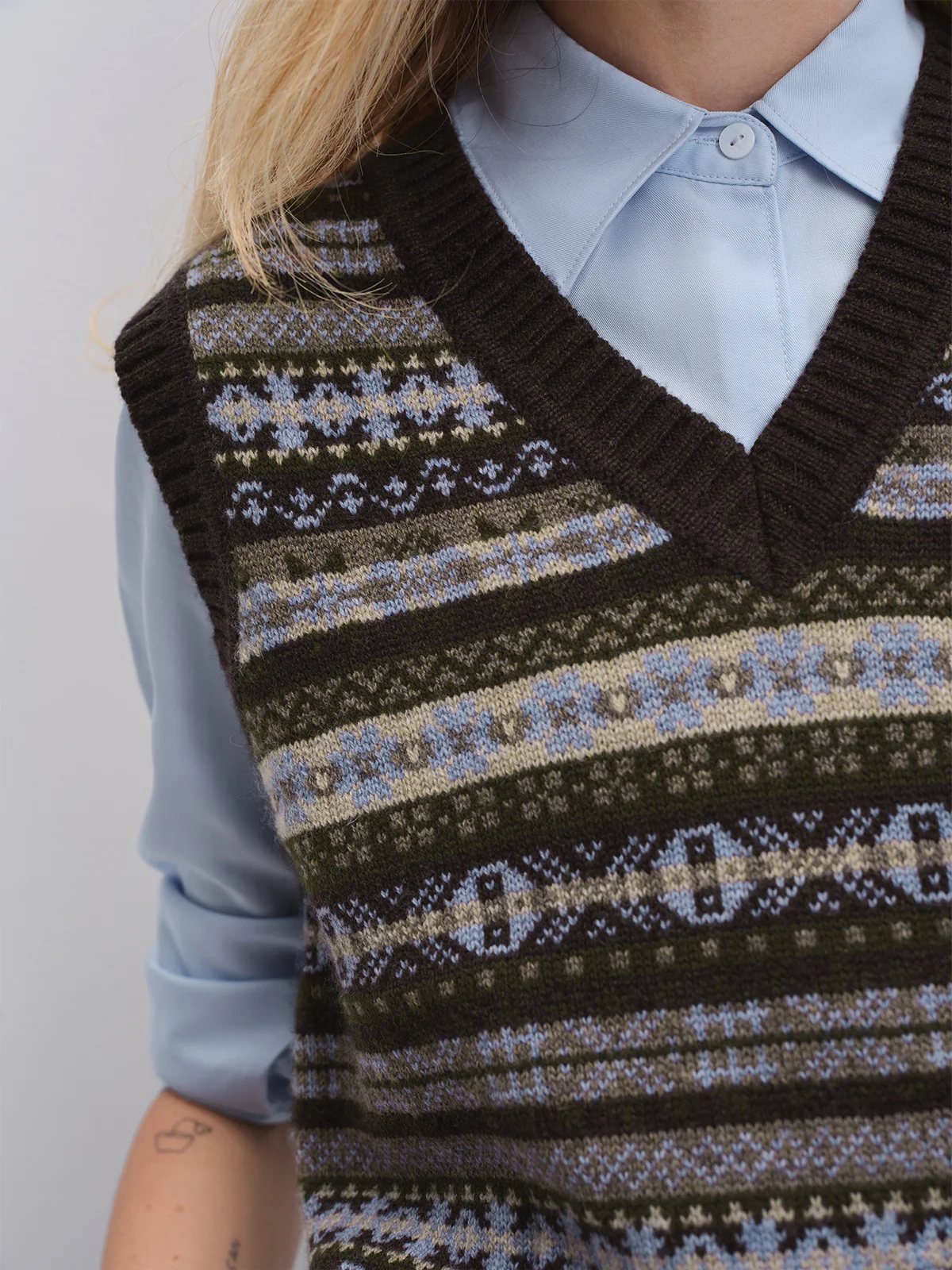 Model in a Brown Fair Isle vest layered over a turtleneck, paired with a skirt and boots.