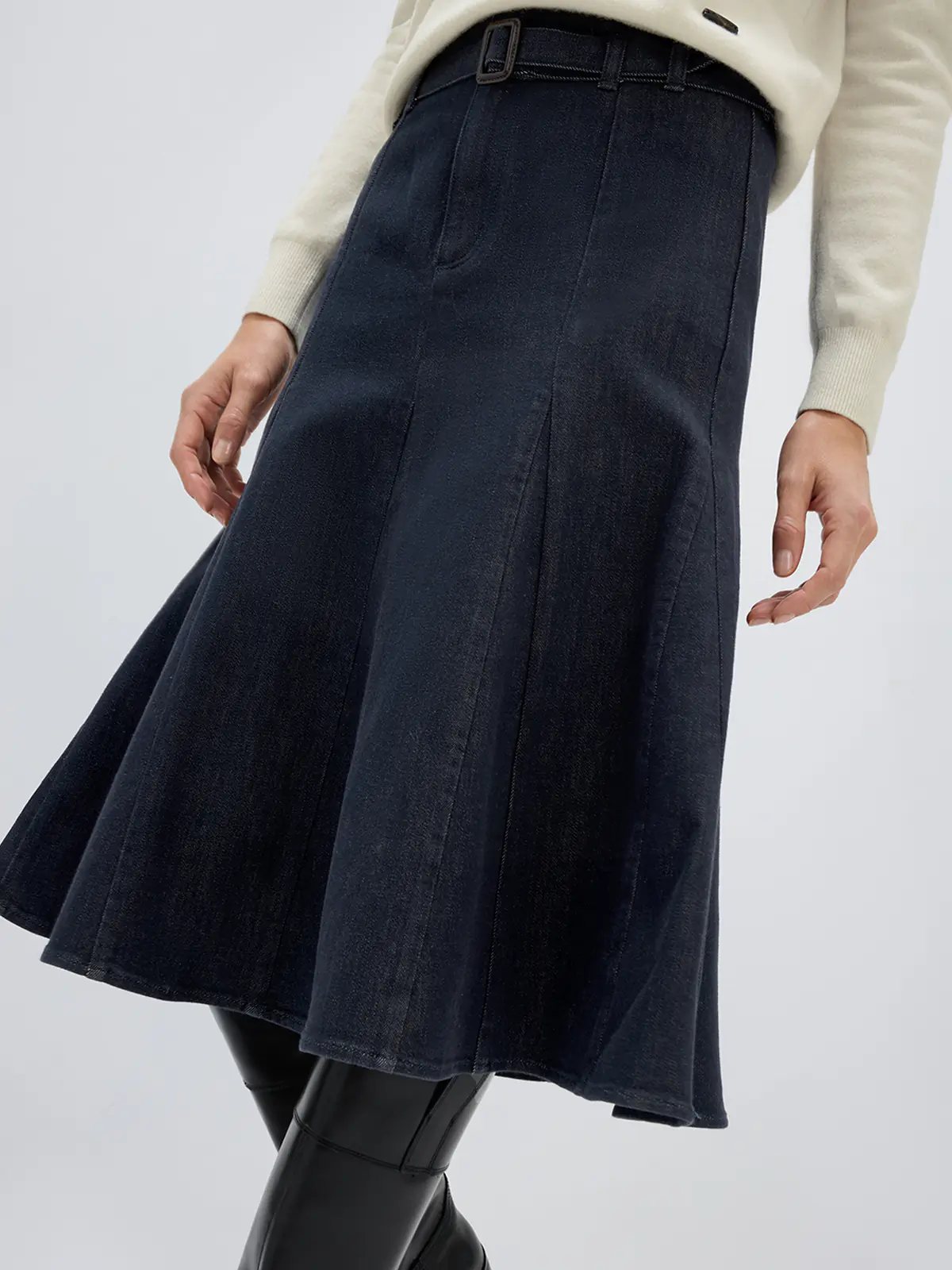 Side view of a model in a Dark Blue fishtail denim skirt with belt, polo shirt, and sneakers.