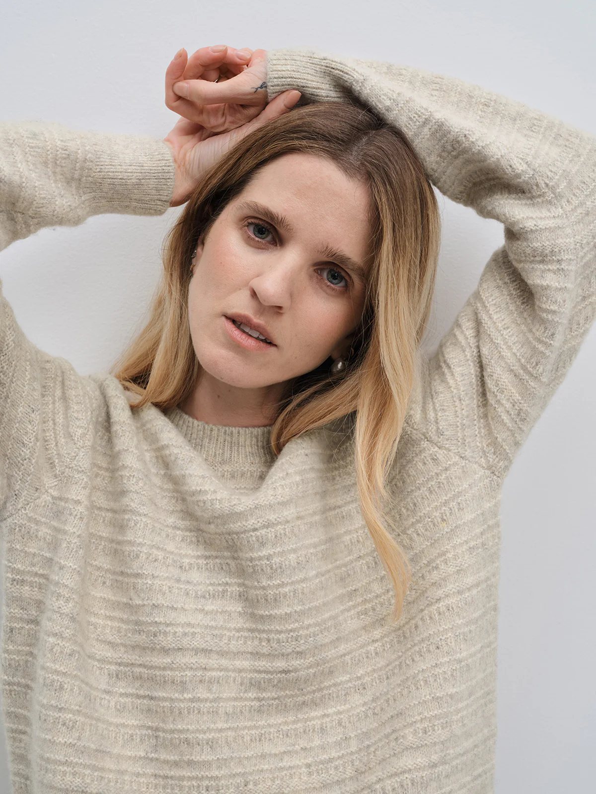 Close-up of andreatang oatmeal wool-cotton jacquard sweater showing painterly stripe texture and ribbed crew neck