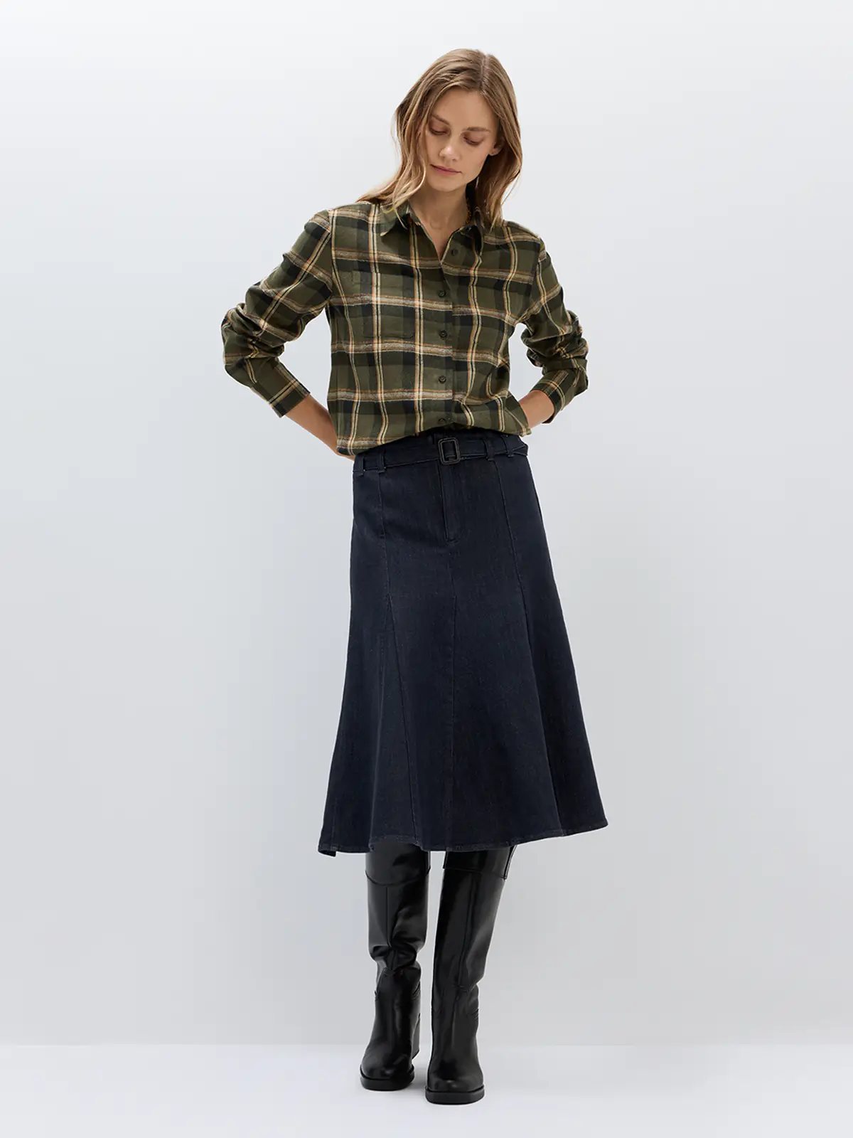 Front view of a model wearing a Dark Blue fishtail denim skirt with belt, V-neck sweater, and knee-high boots.
