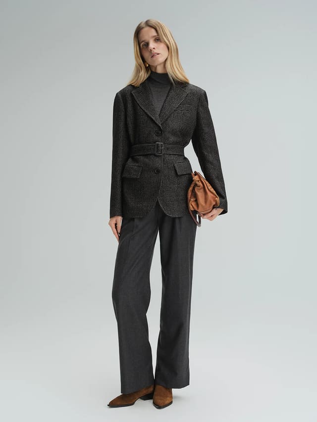 Model wearing andreatang black and grey houndstooth wool-blend belted blazer with wide-leg trousers