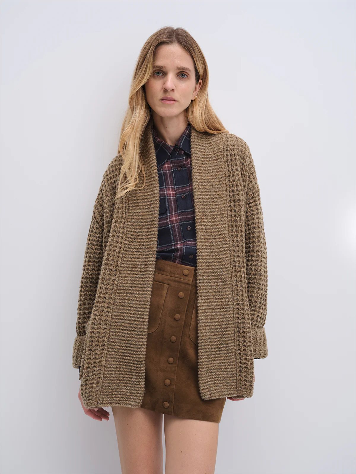 Front view of the Tan textured knit cardigan worn open over a plaid shirt and suede mini skirt.