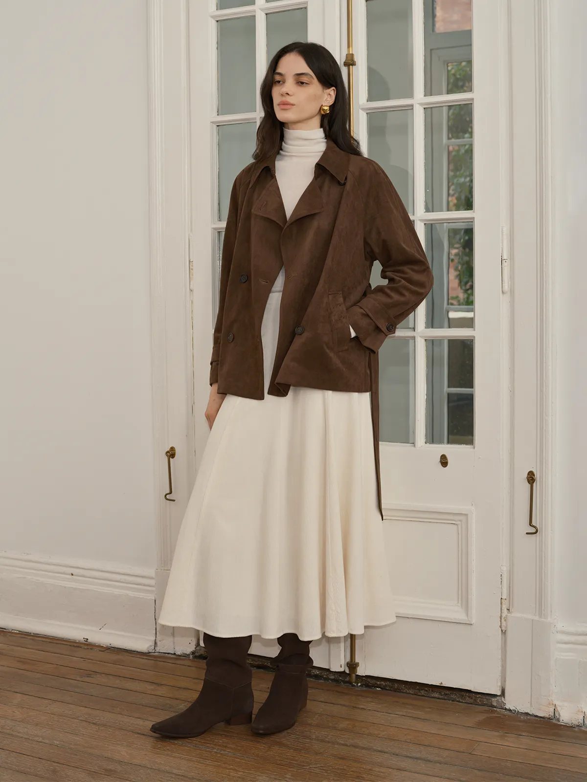 Model in doorway wearing MILIAN corduroy skirt with brown suede jacket and white turtleneck