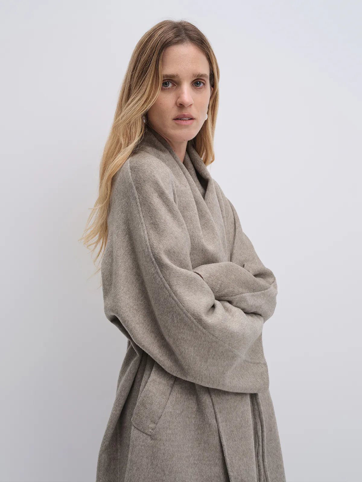Model holding a bag while wearing the Taupe yak wool robe coat, styled with wide-leg jeans and loafers.
