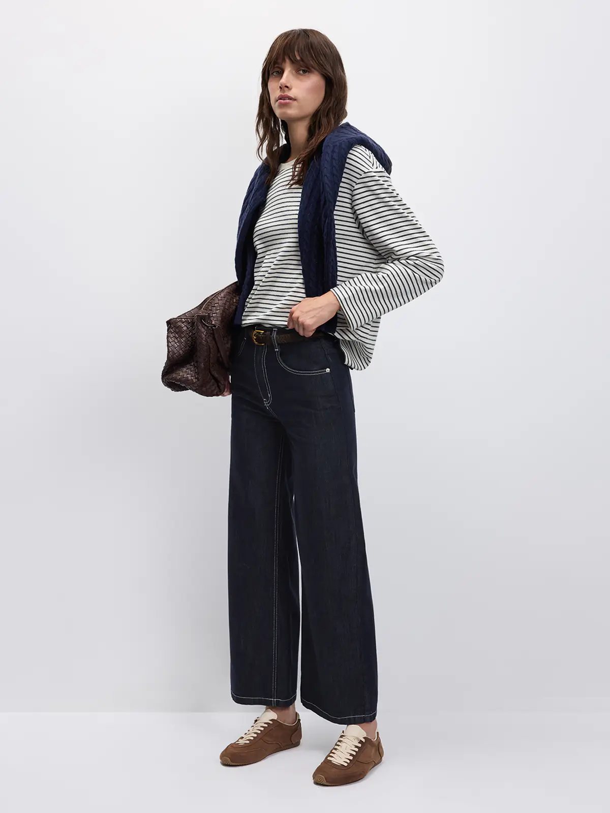 Model standing in side profile wearing a Black/White striped long-sleeve t-shirt layered under a vest.