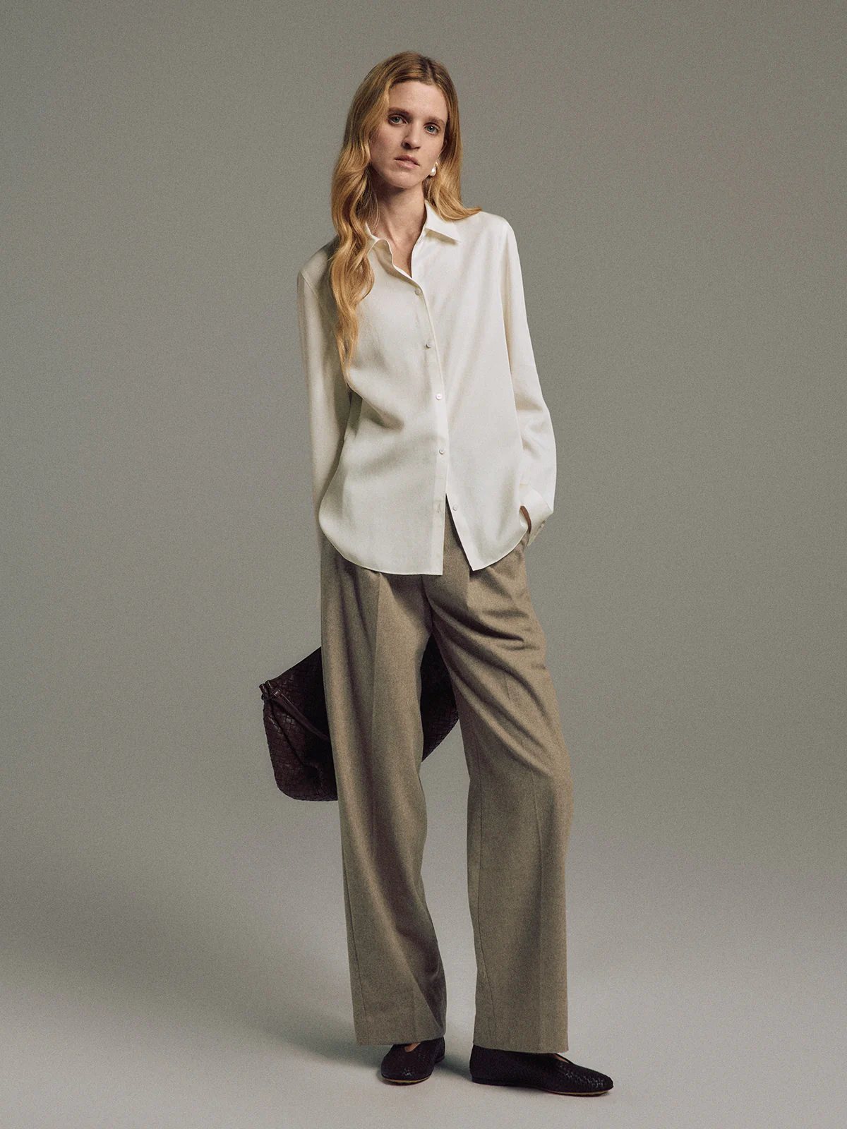 Model wearing Tan wool blend double-pleat straight-leg trousers with blouse and dark shoes, front pose.