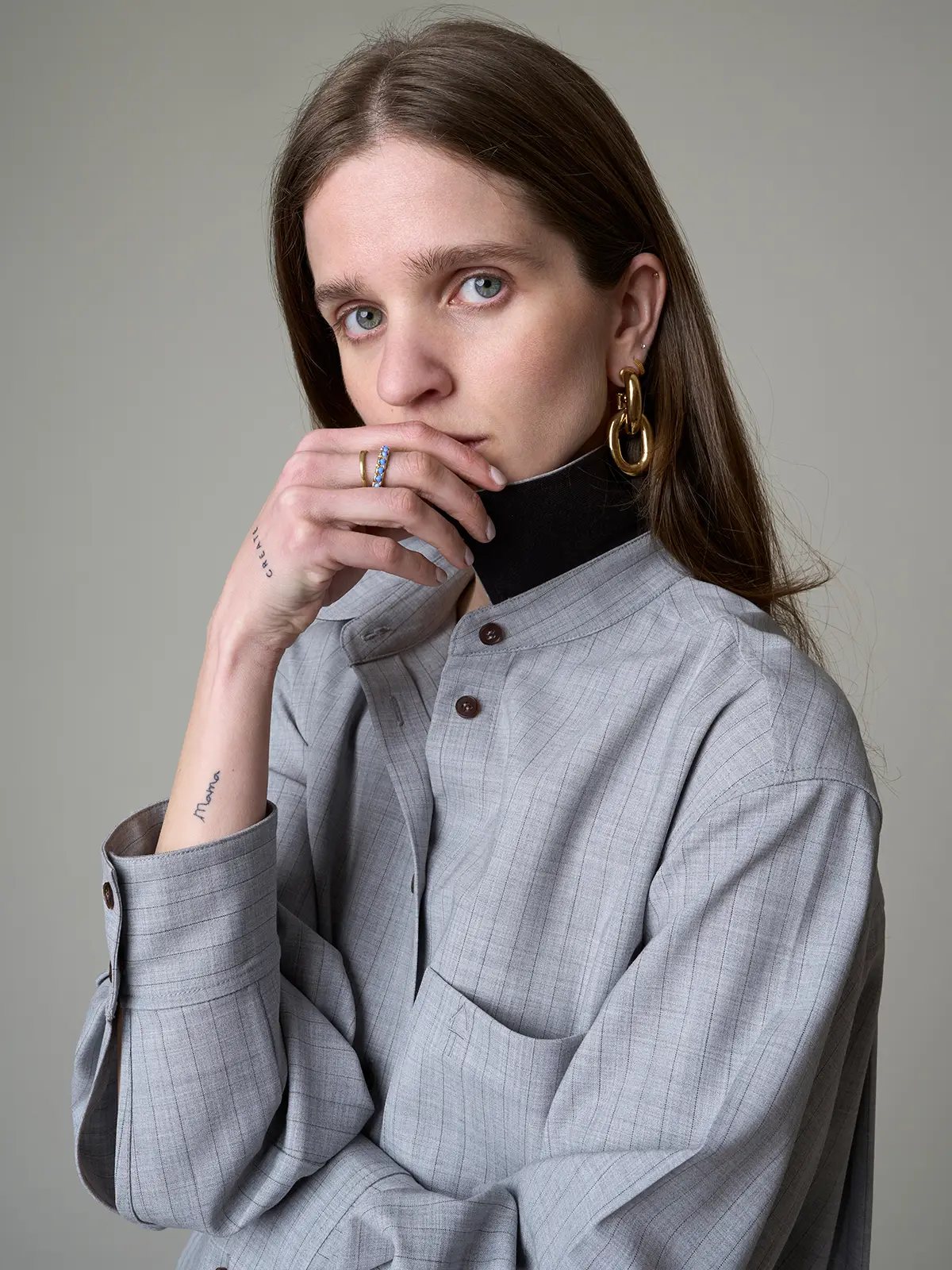 Close-up of model wearing the grey striped loose wool shirt layered over a turtleneck, highlighting collar and cuff details.