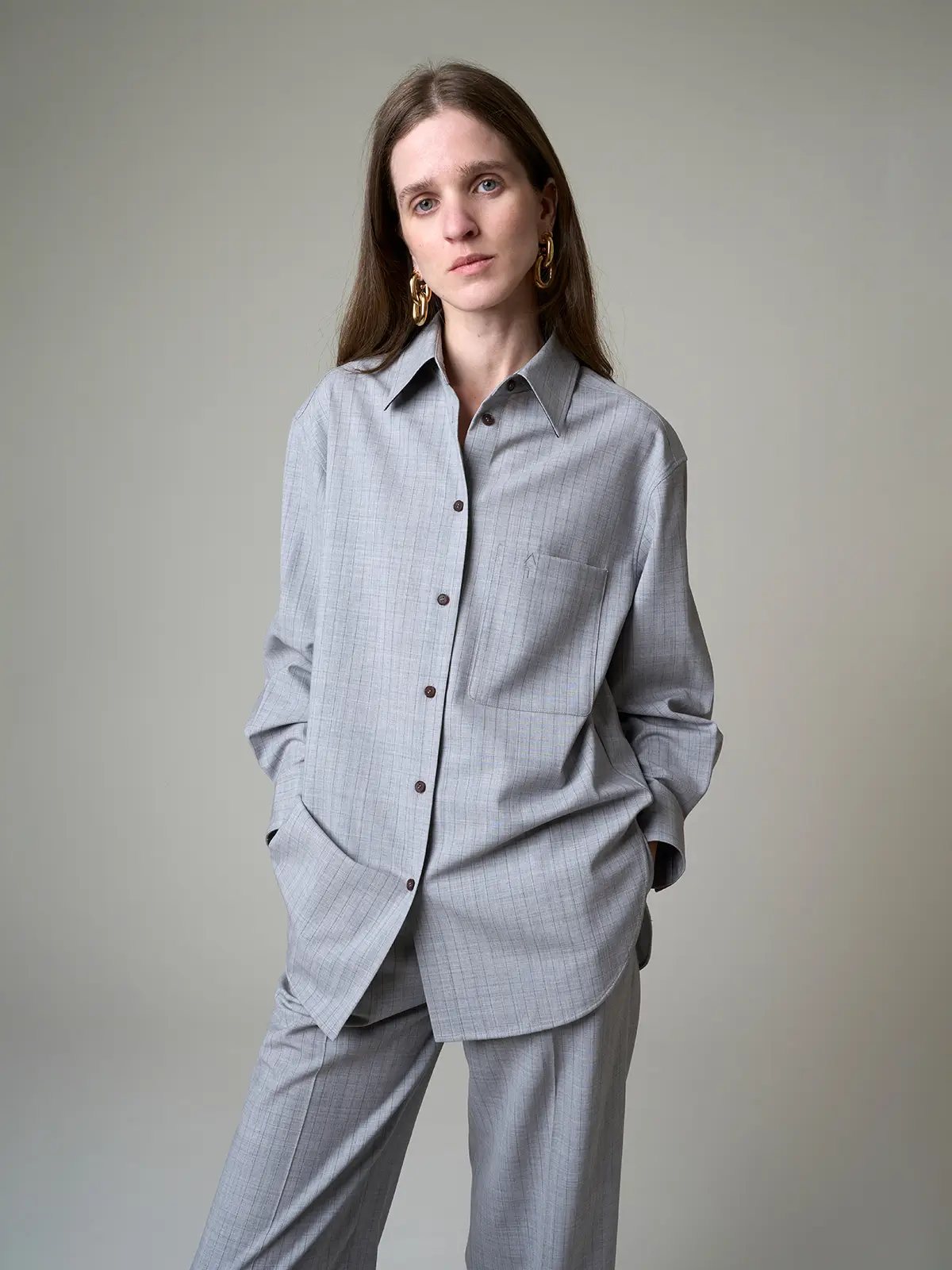Close-up of the grey striped loose wool shirt showing button-front placket, chest pocket, and relaxed fit on model.