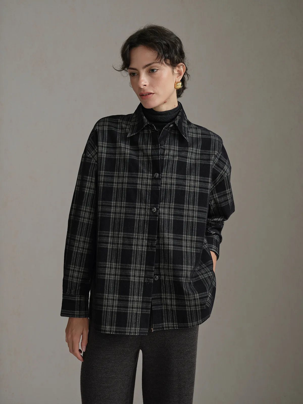 Front view of model wearing ALDER corduroy overshirt buttoned over black turtleneck with charcoal wool pants