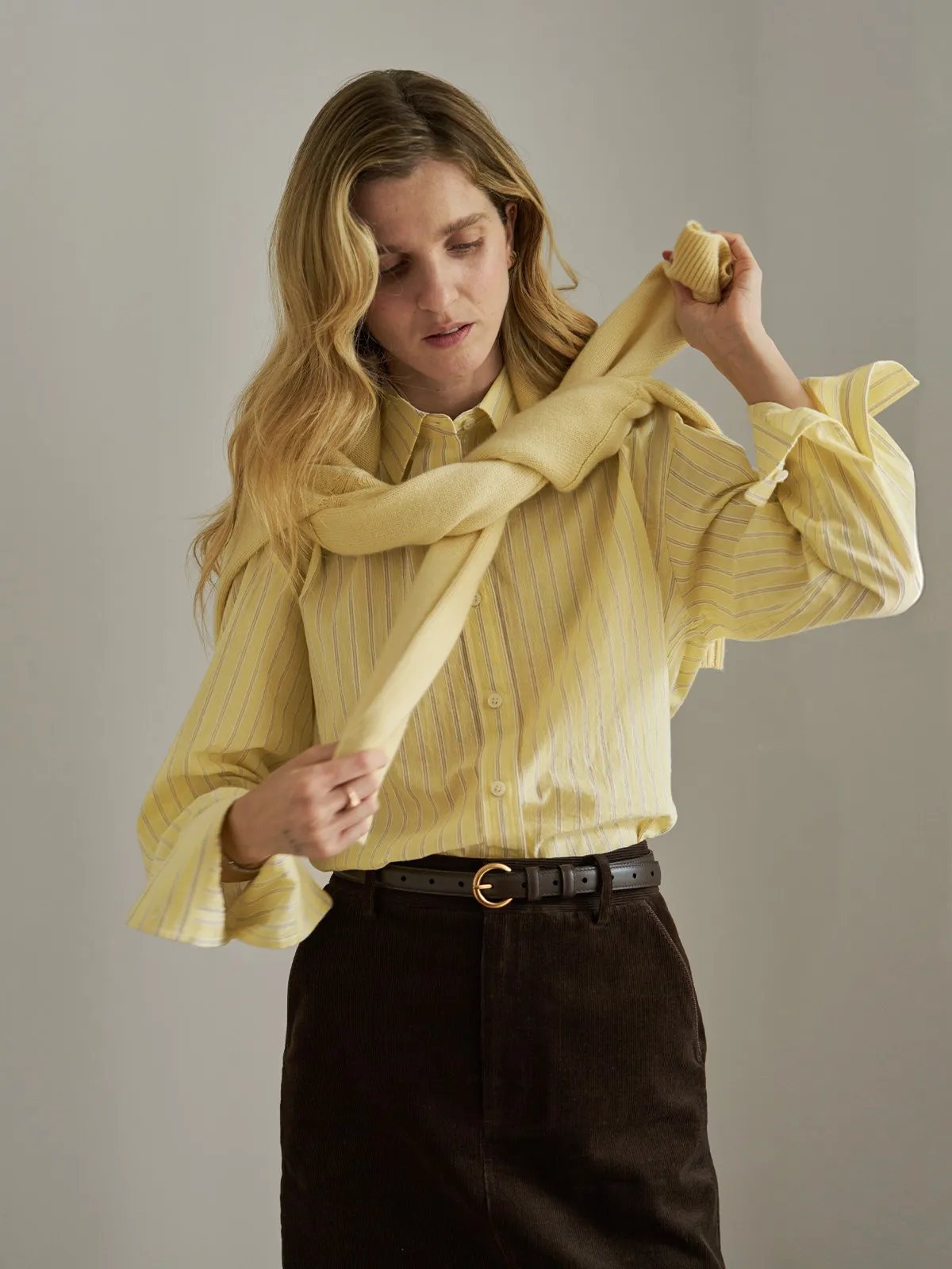 Model draping matching scarf over buttercup seersucker shirt, minimalist layering look