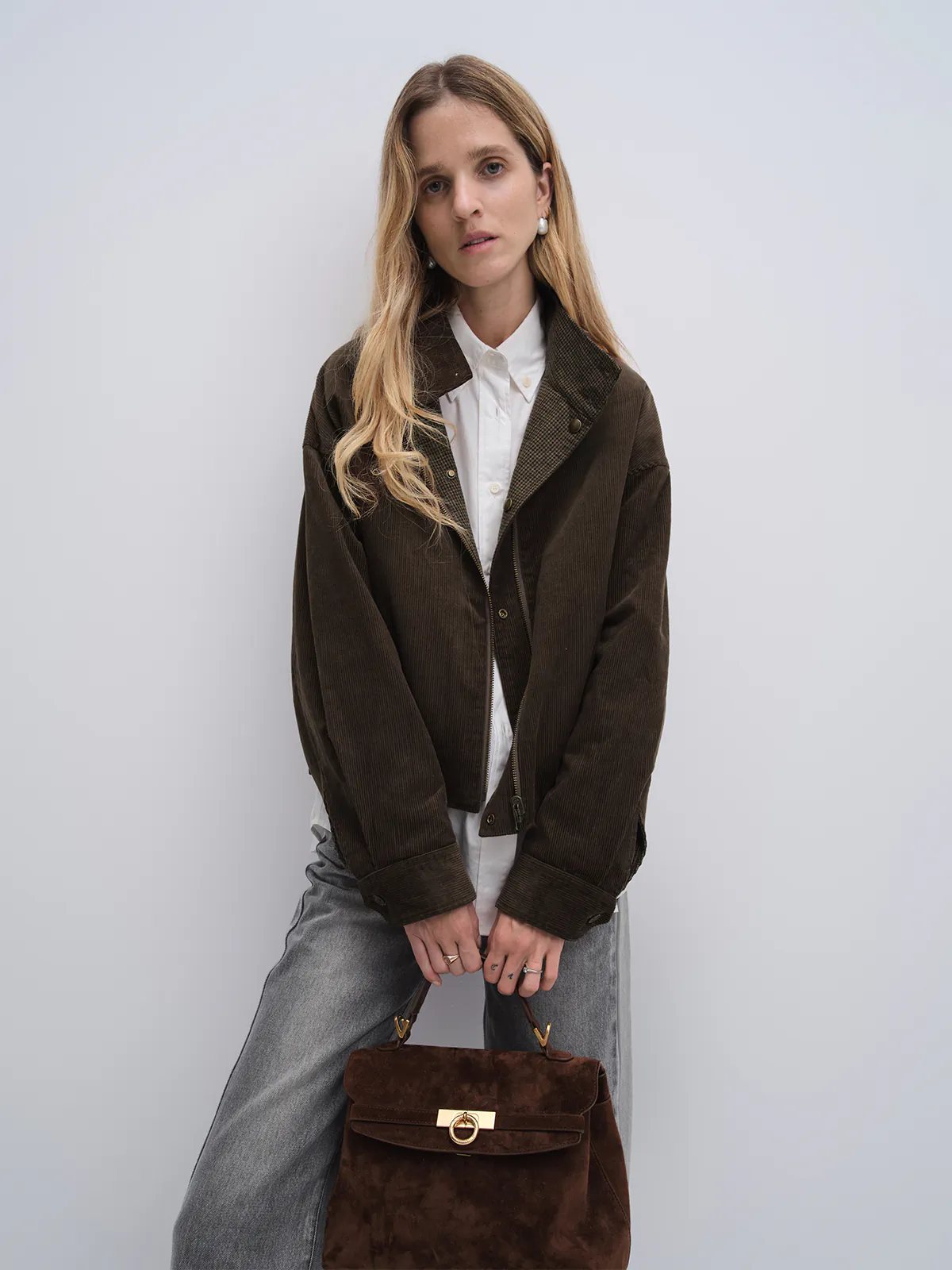Side view of model wearing the Brown houndstooth corduroy reversible jacket over a plaid shirt and brown suede skirt.