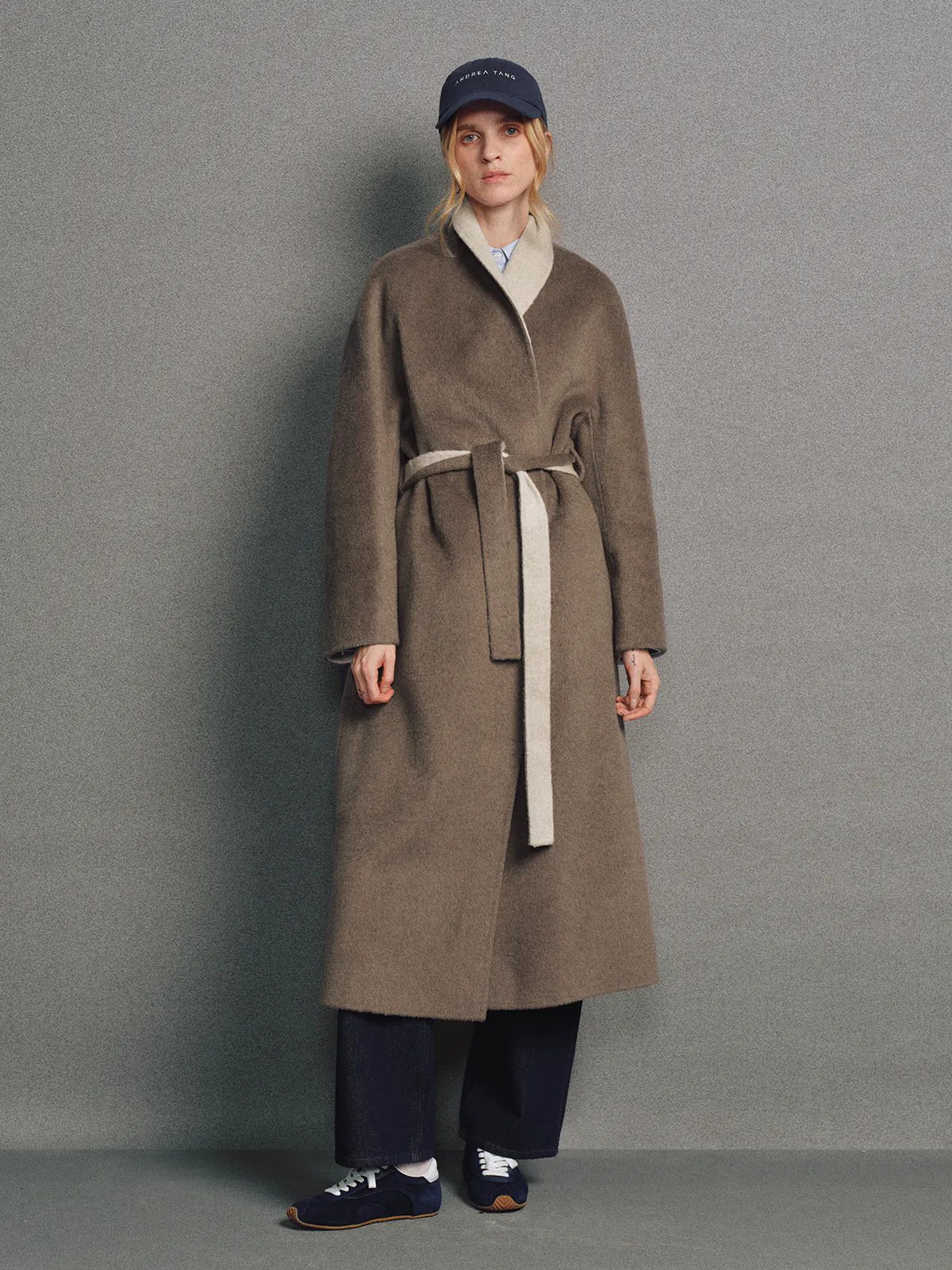 Side view of model in brown two-tone reversible notched-collar coat with lapel and belt, hair down.