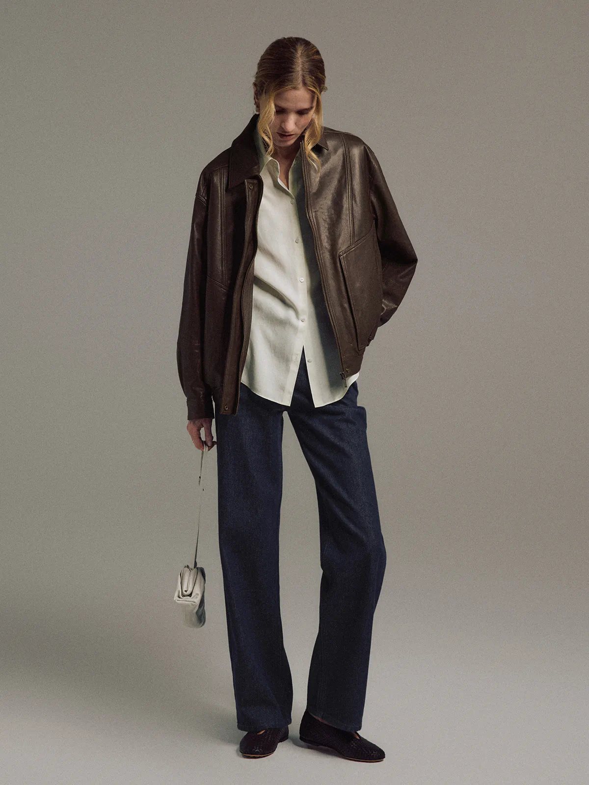 Side profile of model in a Dark Brown Italian shearling leather jacket, open at front.