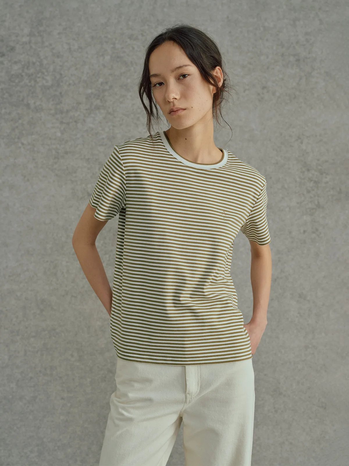 Model in FINLEY striped t-shirt with cream wide-leg trousers, hands in pockets, direct gaze