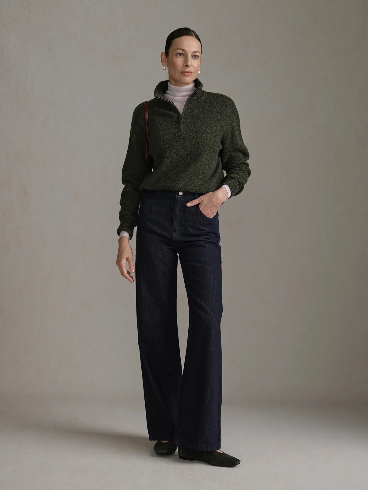 Model wearing CLOVER jeans with hand in pocket, olive sweater, and neutral background