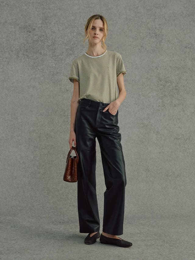 Model wearing FINLEY striped t-shirt with black leather trousers and brown croc-embossed bag, full-body front view